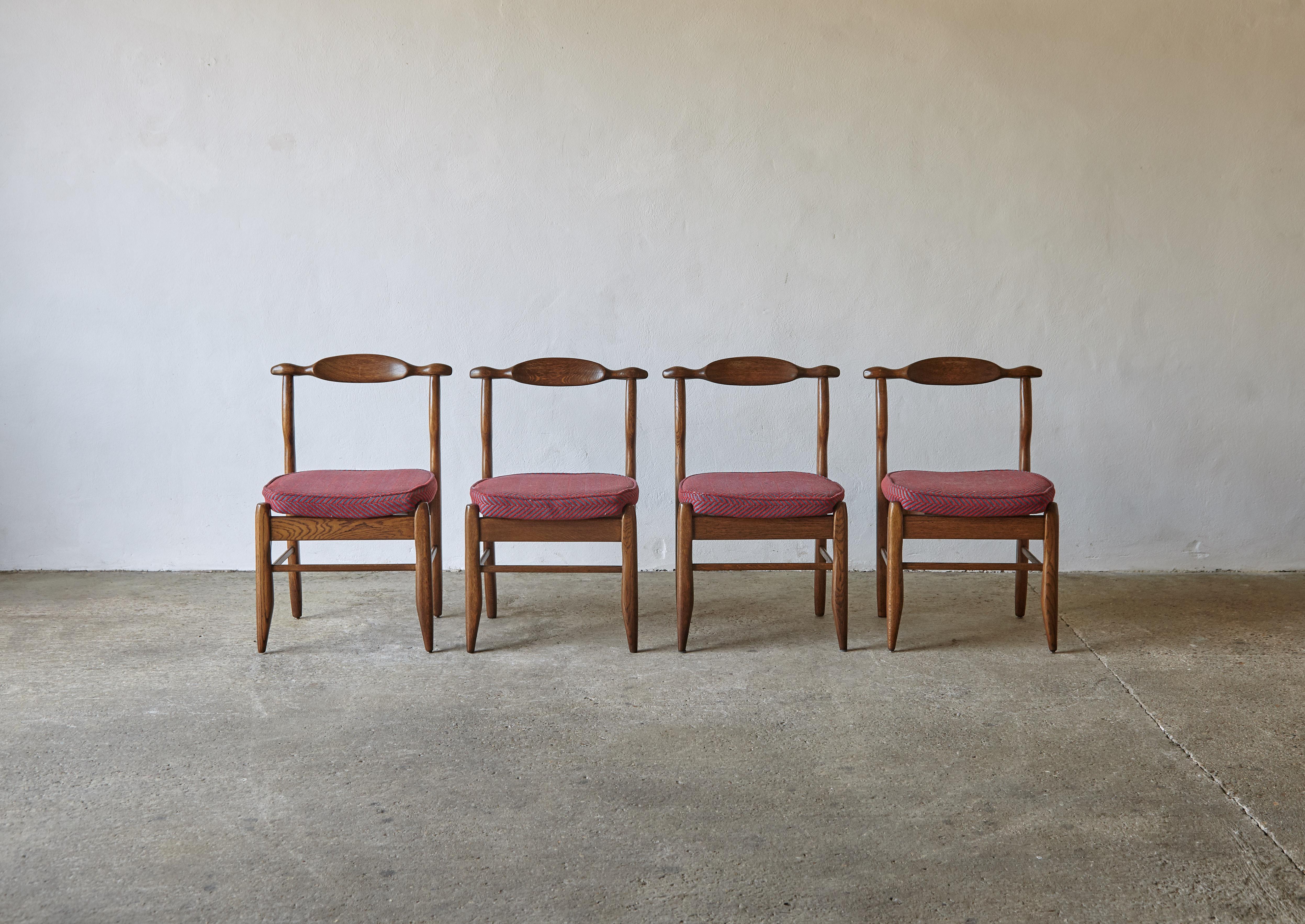 A superb set of four oak dining chairs by Guillerme et Chambron, France, 1960s. The wooden frames are in great condition with a wonderful tone. The seat cushions are in good condition but one has some minor fraying on the piping and a small mark (as