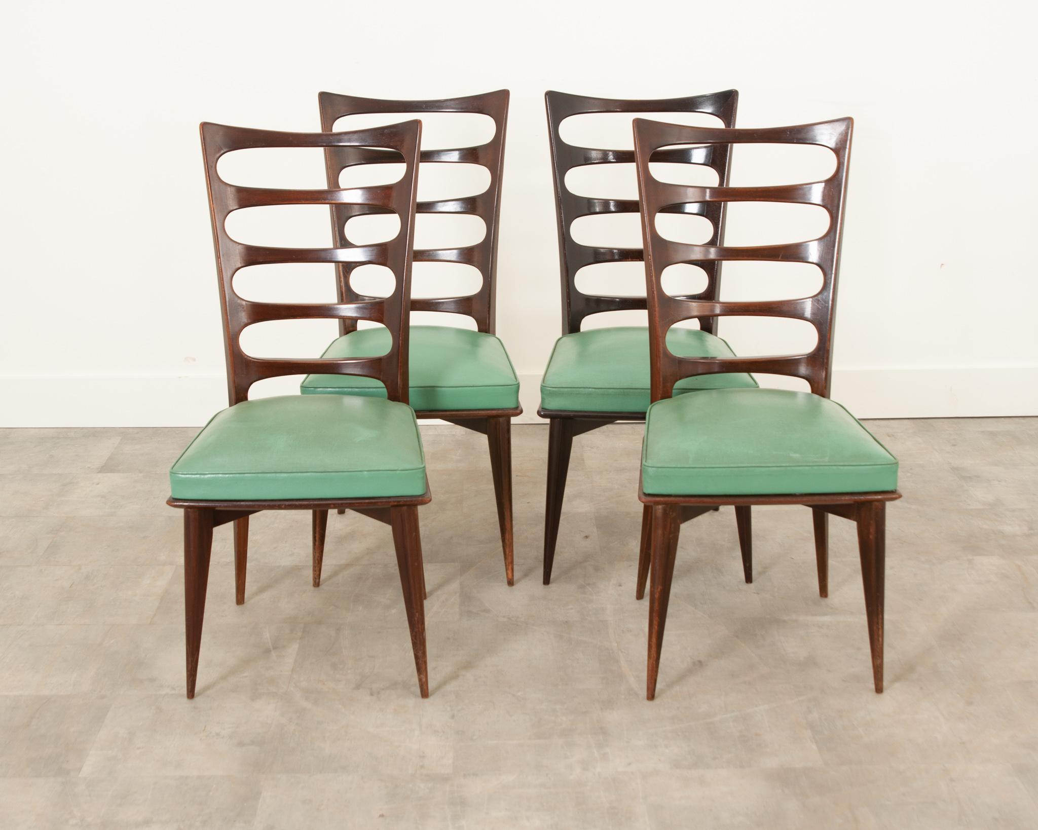 This fine and stylish set of four of mid-century modern mahogany dining chairs are by Gaston Poisson, c. 1960’s, France, and are covered in a teal leatherette that would blend beautifully into almost any color scheme. Seat height: 19″