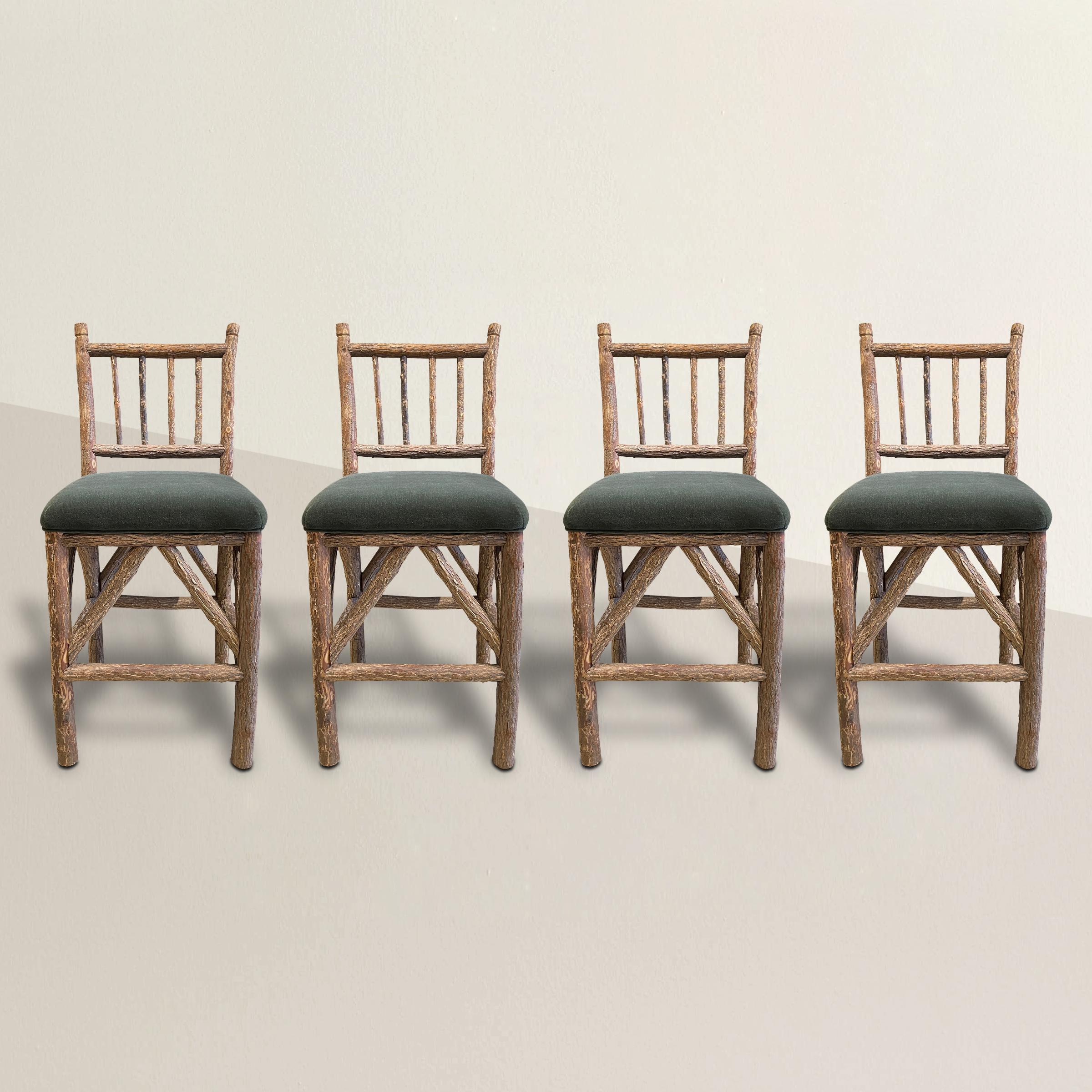 A charming set of four 20th century American Old Hickory bar stools, each constructed hickory branches with the bark left on, and newly upholstered in a gray-green velvet. Perfect at your cabin bar, or at a tall dining table in your breakfast nook.