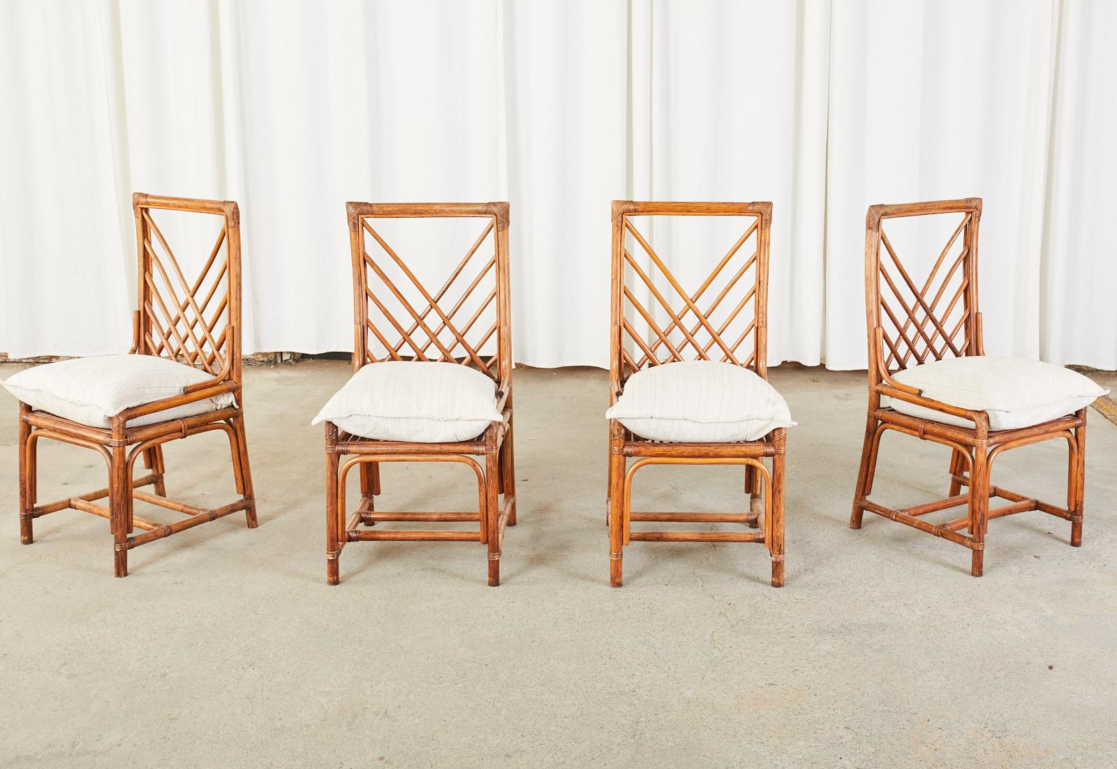 Mid-century set of four dining chairs featuring a rattan wicker frame with a square back having a geometric design splat. Made in the organic modern style lashed together with wicker on the exposed joints. Low side arms measuring 18.5 inches high.