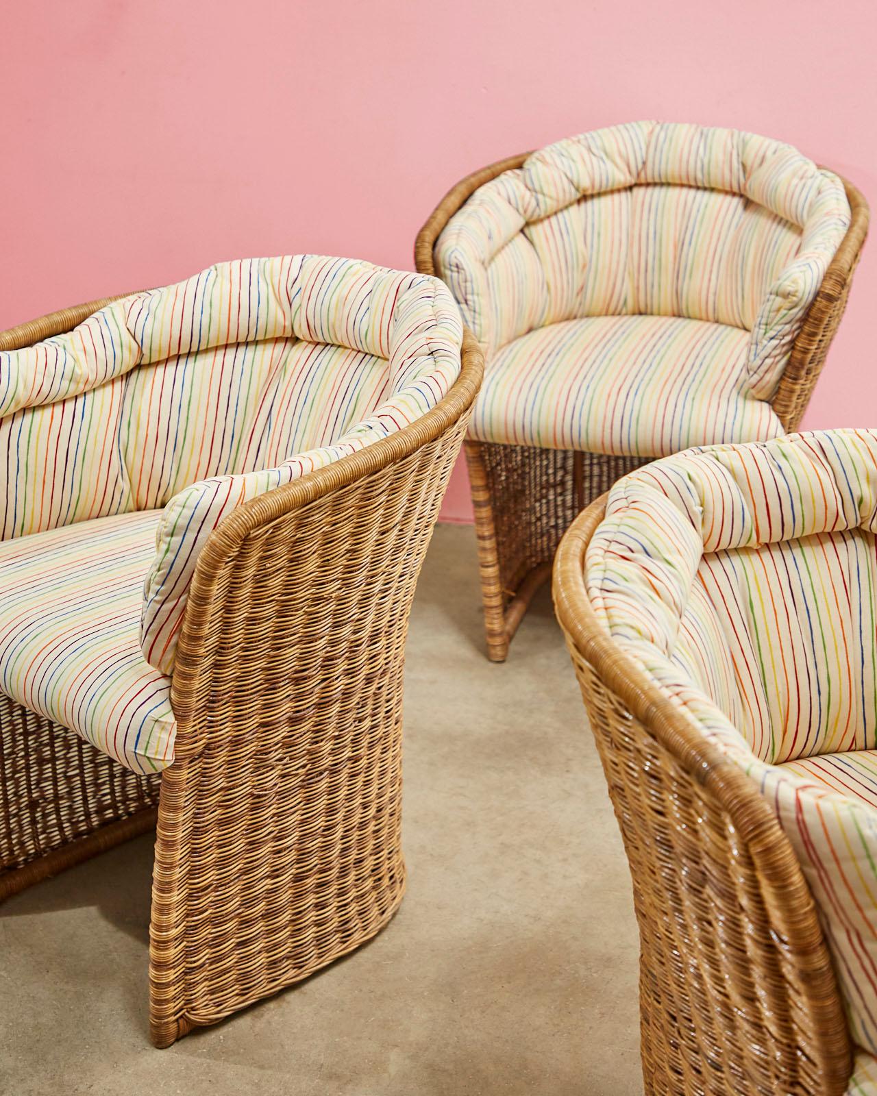 Stylish set of 20th century wicker lounge chairs made in the organic modern style. Featuring a wicker covered frame having a tulip form with a barrel back and a tapered bottom. Unique chairs with padded cushions decorated with a colorful striped