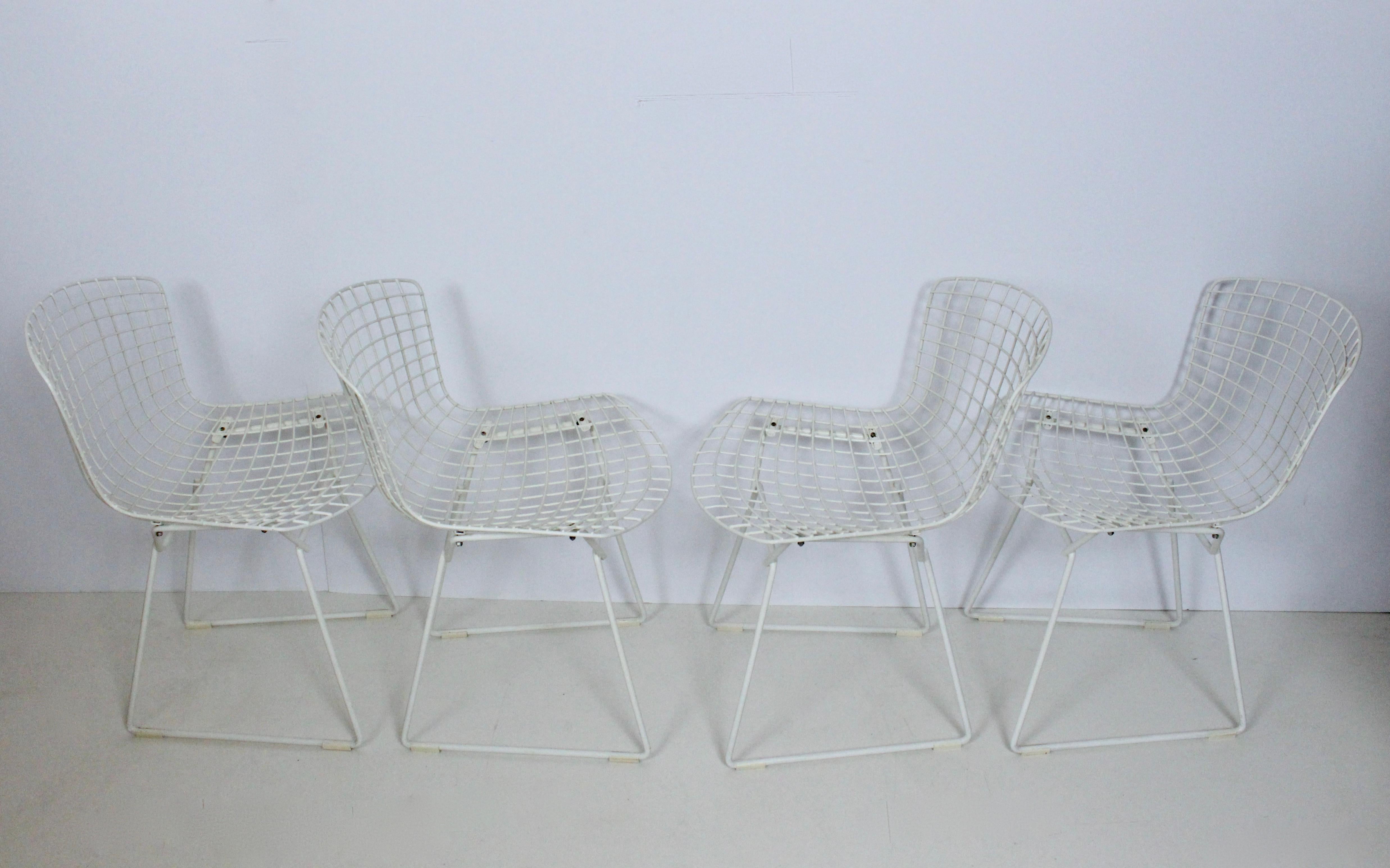 Early set of 4 Harry Bertoia for Knoll indoor outdoor white wire dining chairs. Featuring enameled white wire framework and removable Knoll black vinyl seat cushions. Saw light use. No breaks, repairs or rust. Original paint.
 
