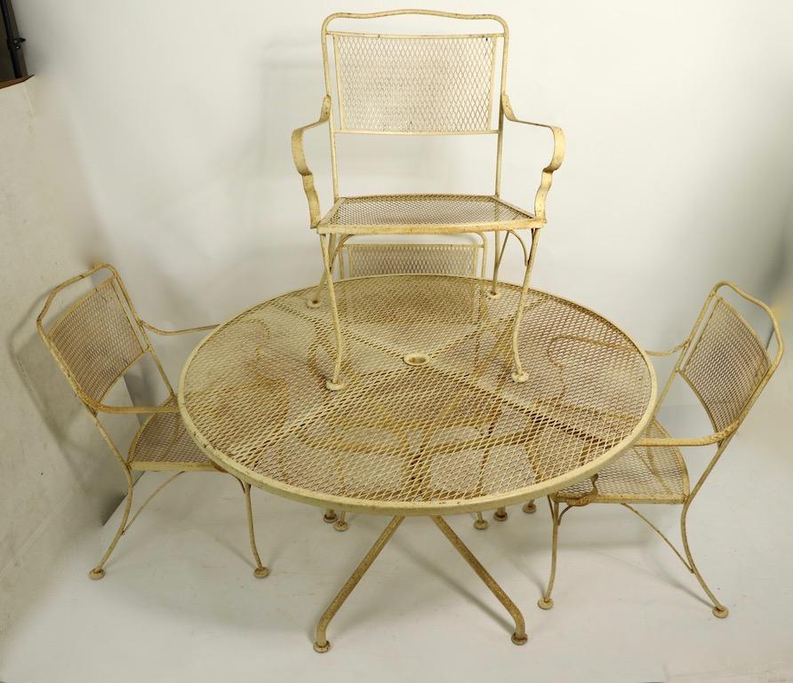 Stylish set of four dining chairs in wrought iron and metal mesh. All are armchairs, This set is currently in original pale yellow paint finish, which shows cosmetic wear normal and consistent with age.. We also offer custom powder coating if you
