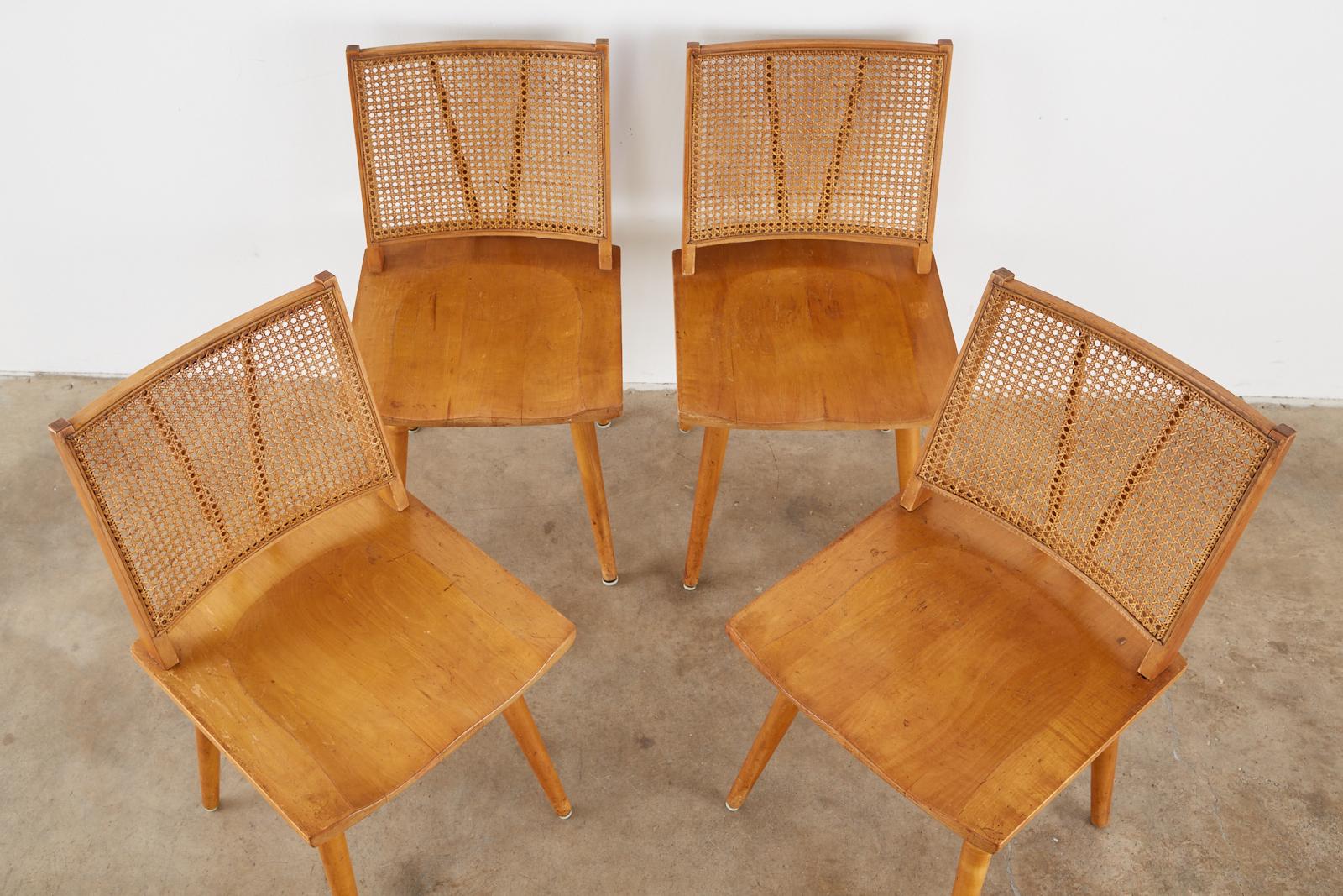 Mid-Century Modern set of four maple dining chairs attributed to Paul McCobb. The chairs feature a caned back conjoined to a shaped saddle seat. Supported by round tapered legs with an H shaped stretcher. Iconic profile with good cane from an estate