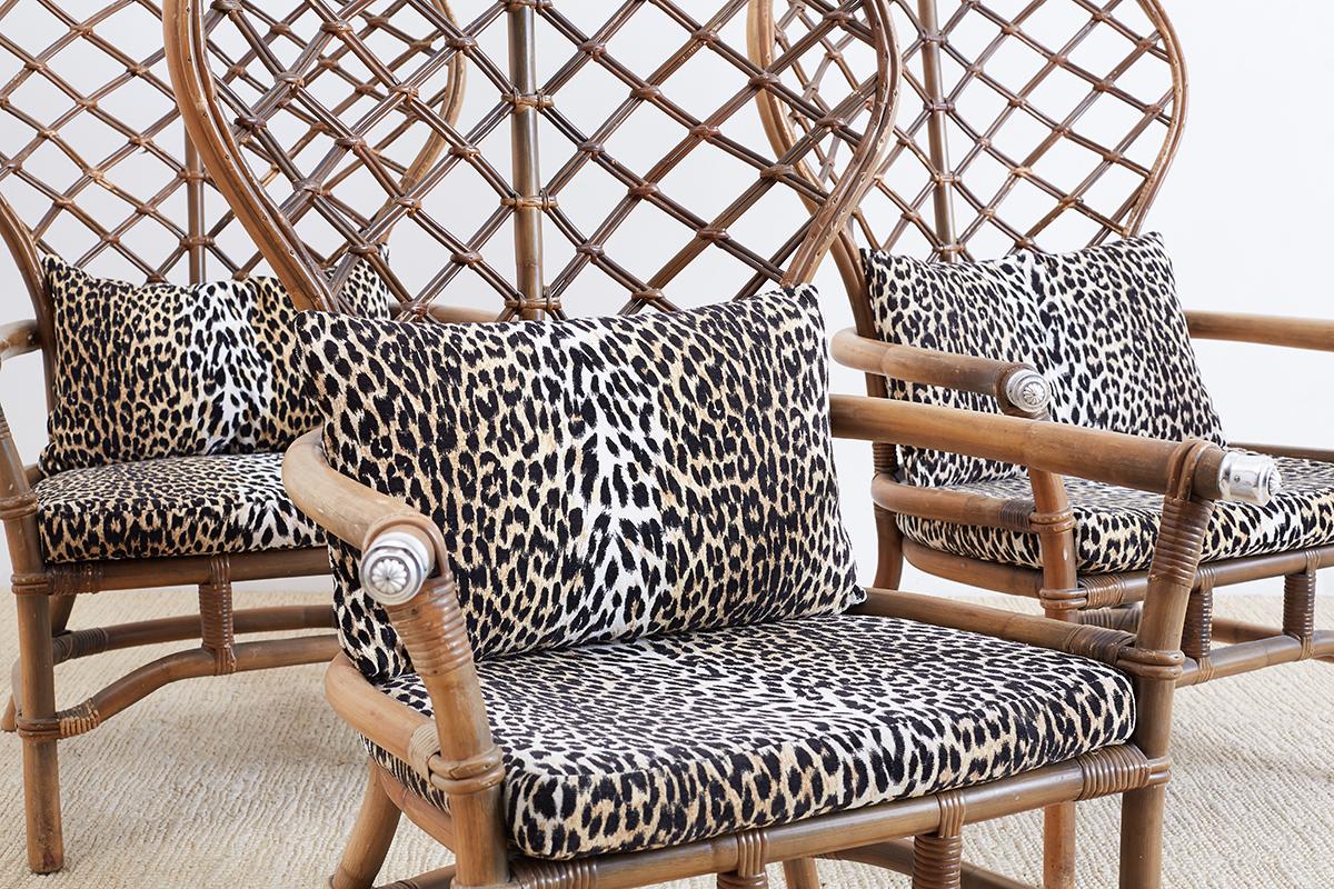 Chic midcentury set of four peacock armchairs made by Ficks Reed in the Hollywood Regency taste. Features an iconic balloon shaped back with an open fretwork pattern design. The rattan frame is reinforced with bamboo strapping and has decorative