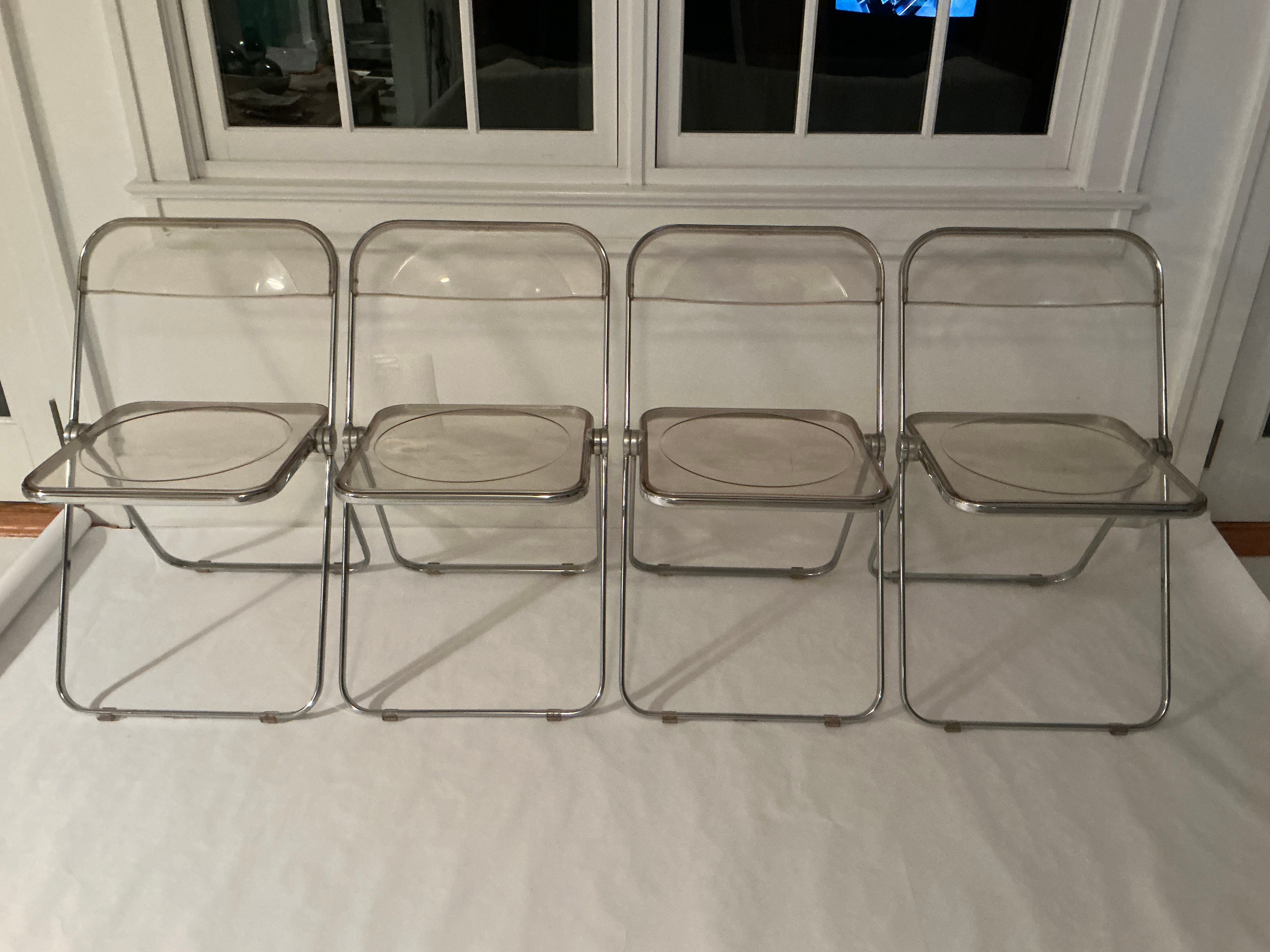 Set of four Plia lucite and chrome folding chairs by Giancarlo Piretti for Castelli. The Plia chair is a classic design made in Italy and is a part of the MOMA design collection . The chairs fold easily and flat for easy storage. 