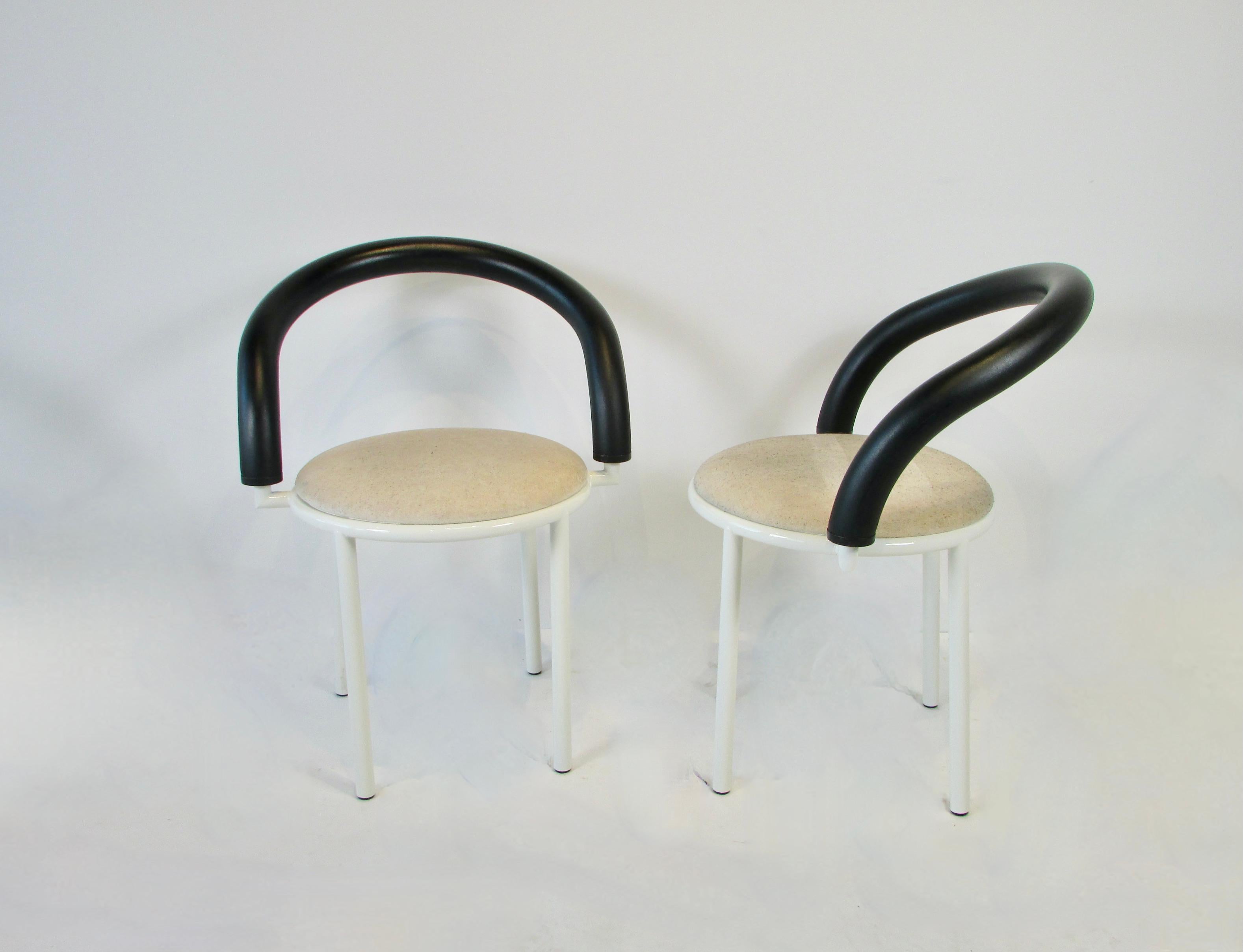 Set of four Memphis era post modern armchairs. Designed by Italian designer Anna Anselmi. Curve around pretzel style arms are covered in dense rubber / foam. Steel bases are finished in white lacquer. Seats are supple foam with a cloth cover still
