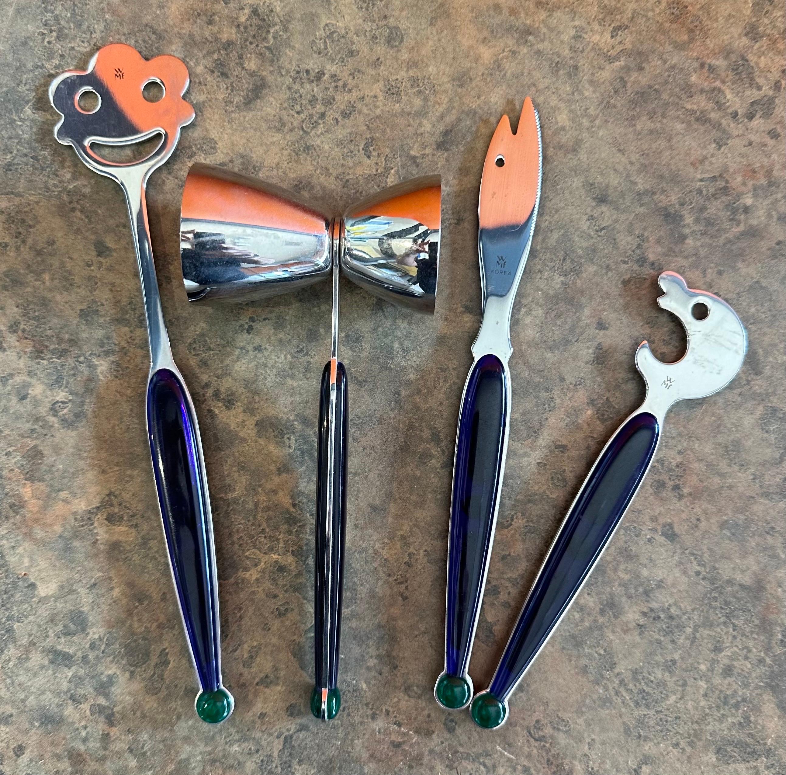Set of four post-modern stainless steel barware tools with purple and green plastic handles, circa 1980s. The set includes a bottle opener, stir citrus knife and double sided pour cup all made of stainless steel. The tools are in very good condition