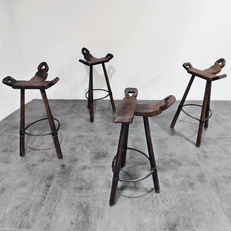 Handsome set of four tripod bar stools with hand-wrought iron footrest.
Four Marbella bar stools in stained oak wood and with a metal ring in the style of Sergio Rodrigues. The curved T-shape seat makes the seating very comfortable. The three