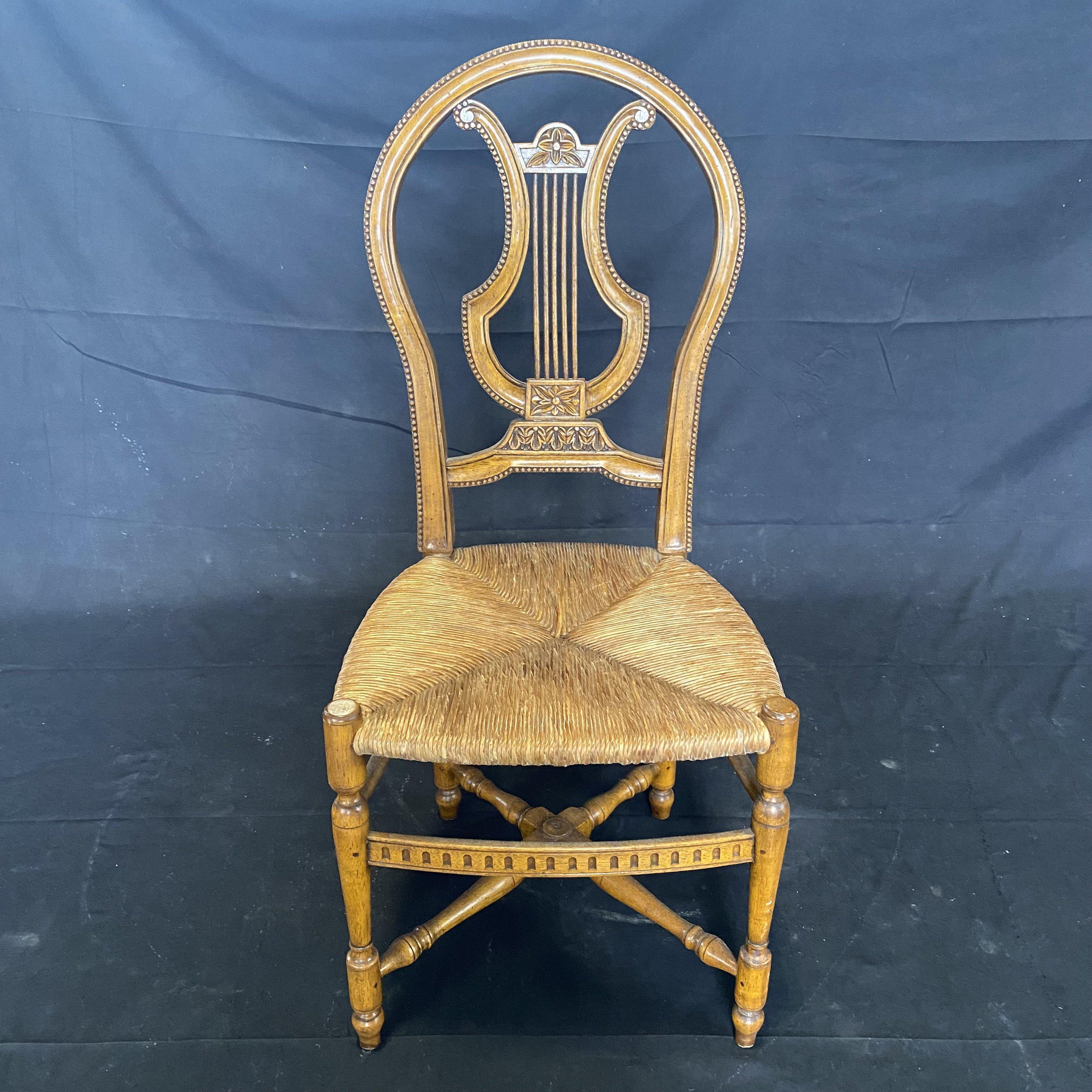 A lovely set of four French lyre back highly detailed side chairs having rush seats, carved walnut reeded and floral motif and turned crossed stretchers.

#5556.