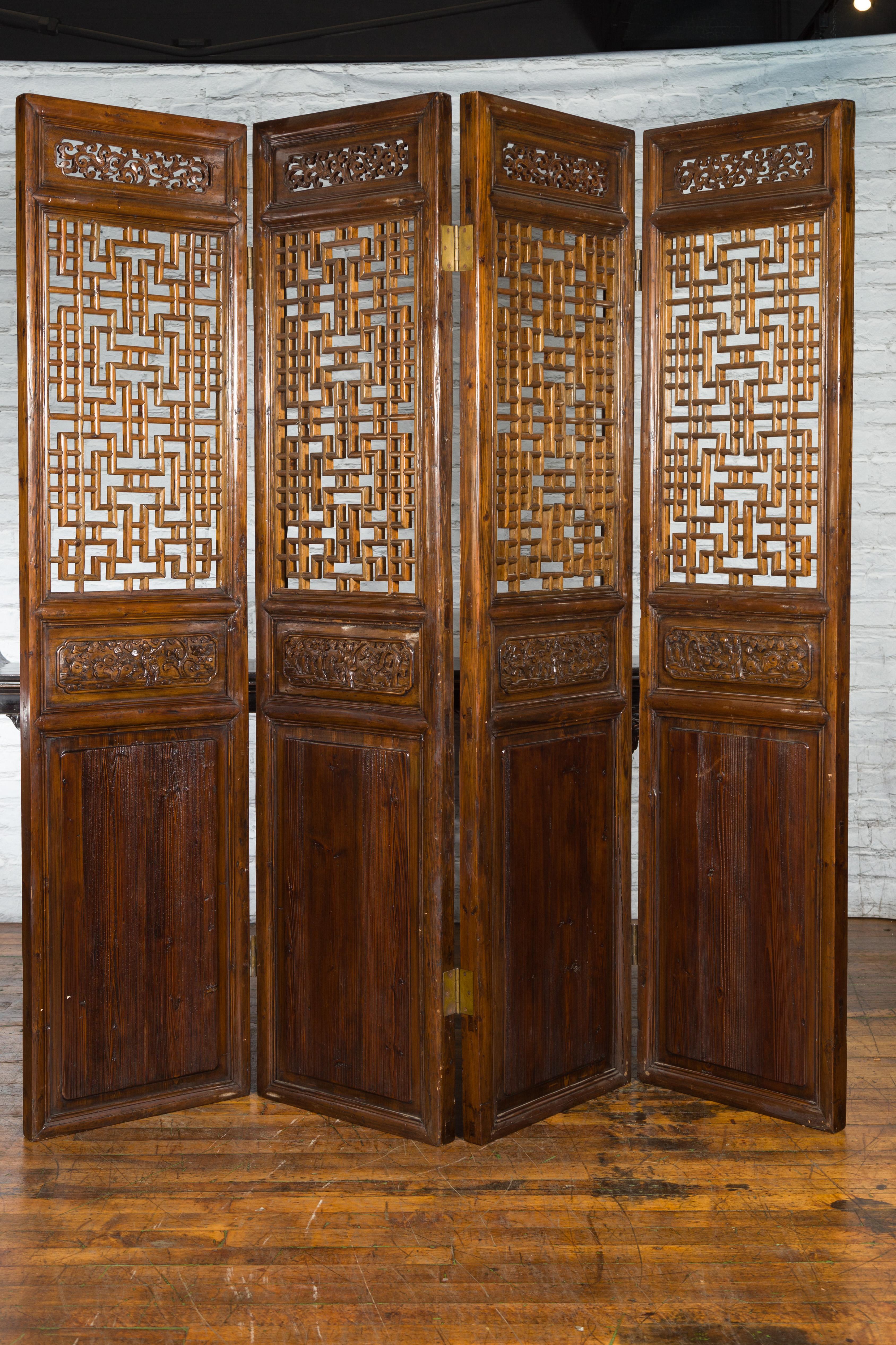A set of four Chinese Qing Dynasty period large carved elm wood interior door panels from the late 19th century, with fretwork design, openwork and figures in landscape scenes carved in low relief. Created in China during the Qing Dynasty in the