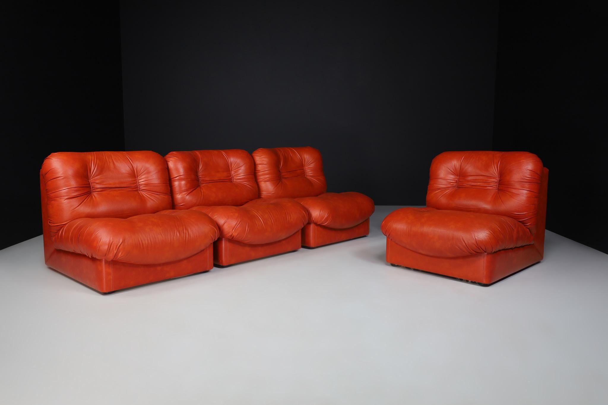 Ensemble de quatre fauteuils/sofa de salon en cuir rouge, Italie 1970

Ce design se caractérise par une forme en L reposant sur deux coussins touffetés reliés entre eux. Cela donne à la chaise un aspect volumineux et ludique. Nous avons