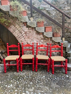 Juego de cuatro sillas con respaldo en forma de escalera y asiento de junco pintadas de rojo