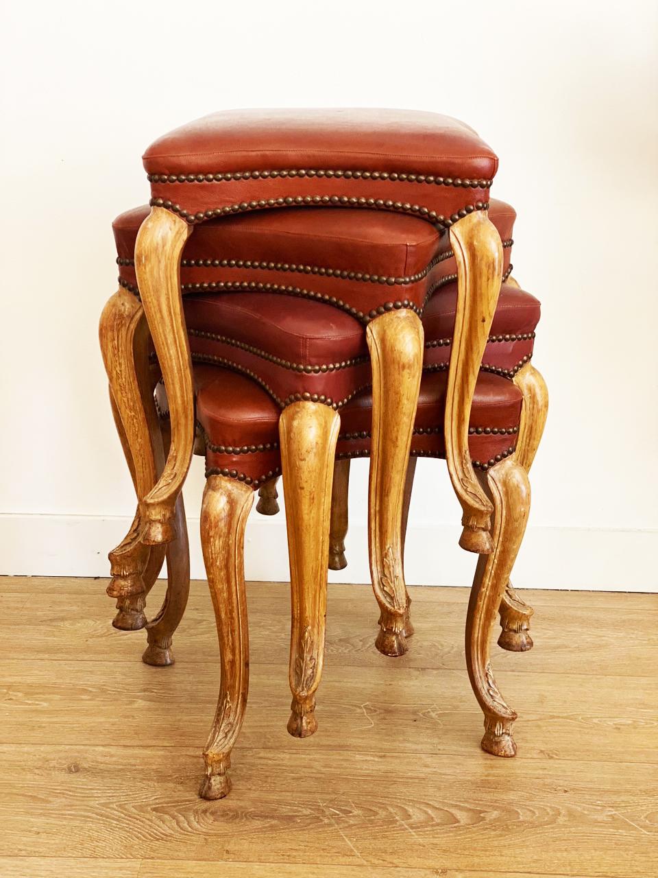 Rare set of four Regence style stackable stools, 
Walnut cabriole legs terminating in hoof feet
Original Bordeaux leatherette bordered with antique patinated brass tack nail heads
Attributed to Maison Jansen, France circa 1940
Provenance