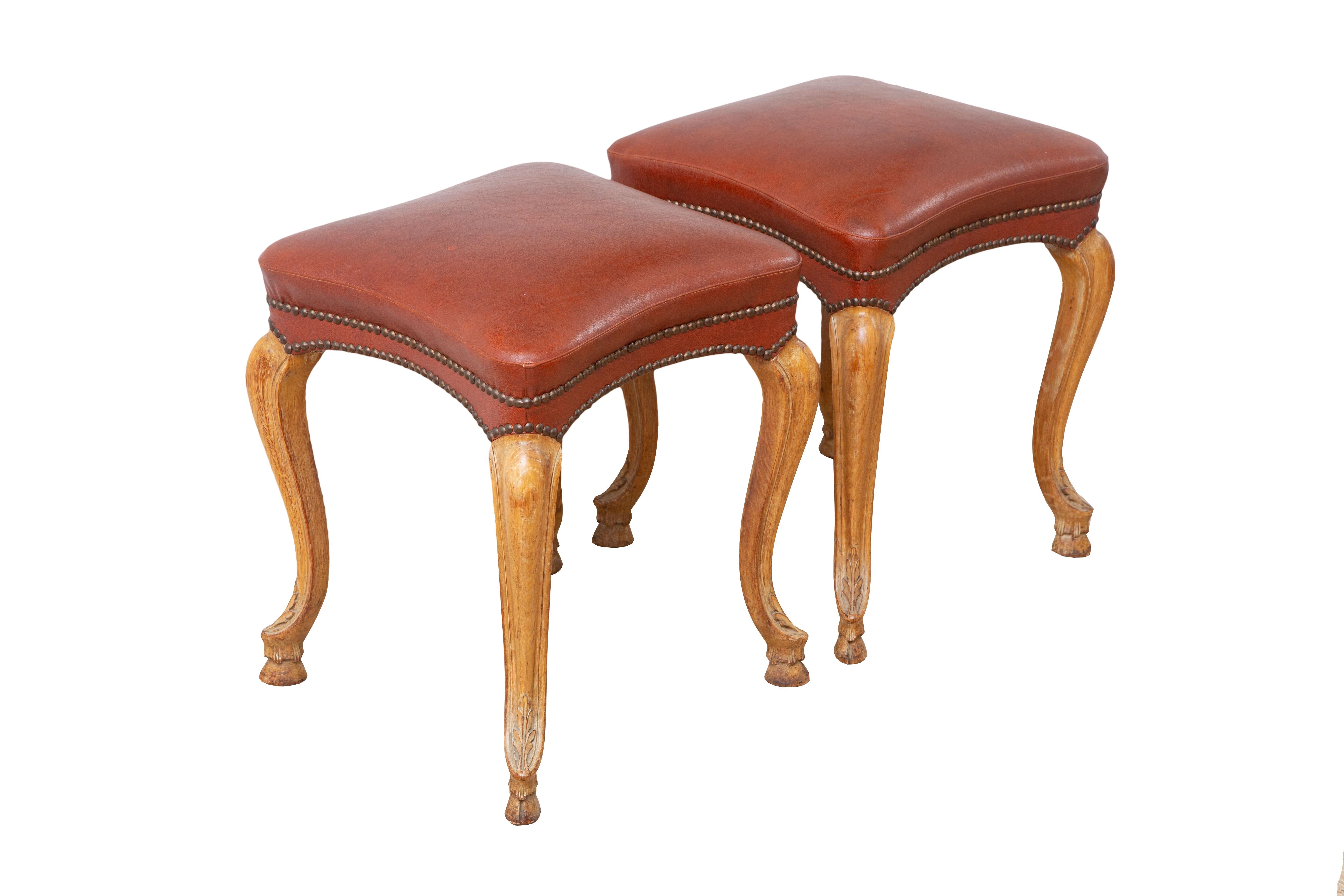 Rare set of four Regence style stackable stools, 
Attributed to Maison Jansen circa 1940. The stools feature beautifully carved walnut cabriole legs terminating in hoof feet. Original Bordeaux leatherette, antique brass nails adorn the hedges.

