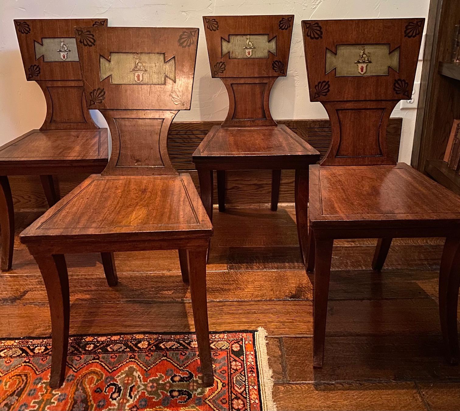 Stunning set of four Regency period mahogany and ebony inlaid armorial hall chairs, possibly attributable to Marsh and Tatham. The backs are decorated with anthemions and with the arms of the Sebright family. 

Provenance: Sir John Saunders