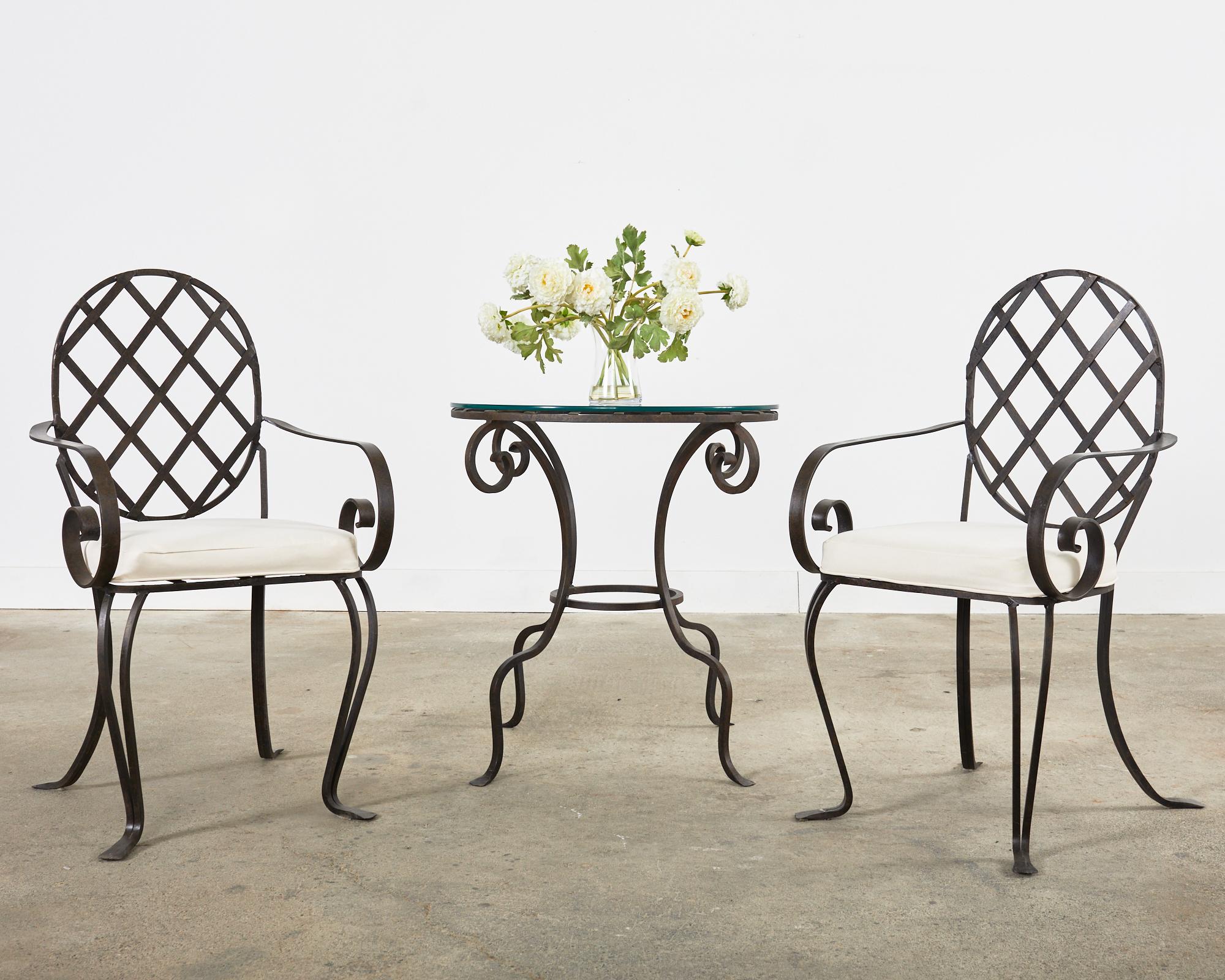 Distinctive set of four wrought iron patio and garden dining armchairs featuring an iron lattice inset seat and back in the style of Rose Tarlow Melrose House, Los Angeles, CA. Produced by a foundry in Los Angeles with oval or cameo shaped backs