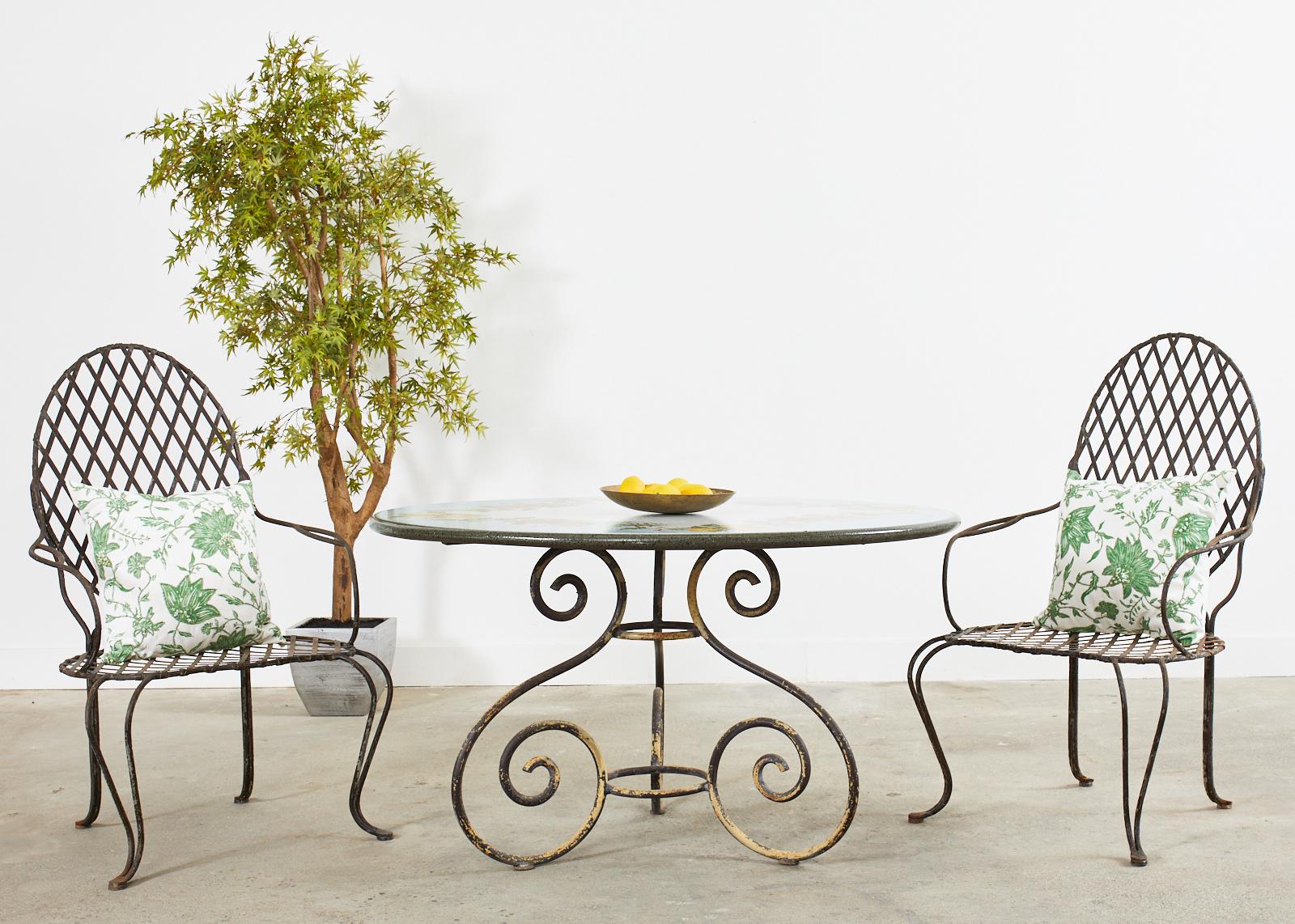 Gorgeous set of four iron patio and garden dining armchairs attributed to Rose Tarlow Melrose House Los Angeles, CA. The set features a large faux bois twig motif iron frame with geometrical lattice inset. The iron has an intentionally aged,
