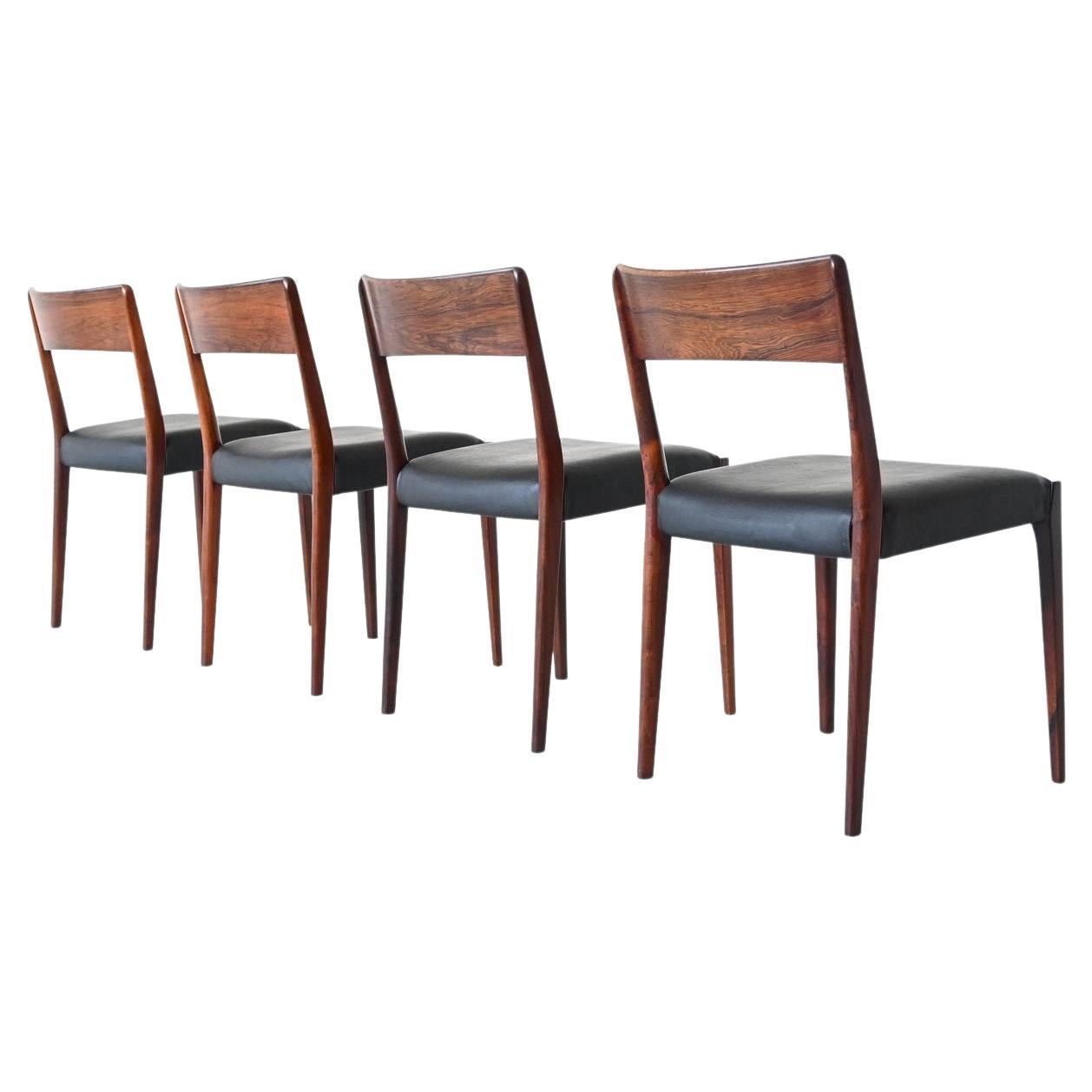 Beautiful shaped set of four dining chairs manufactured by Hornslet Møbelfabrik A/S, Denmark 1960. These chairs are made of amazingly grained solid rosewood and they are upholstered with black faux leather. The dining chairs are in very good /
