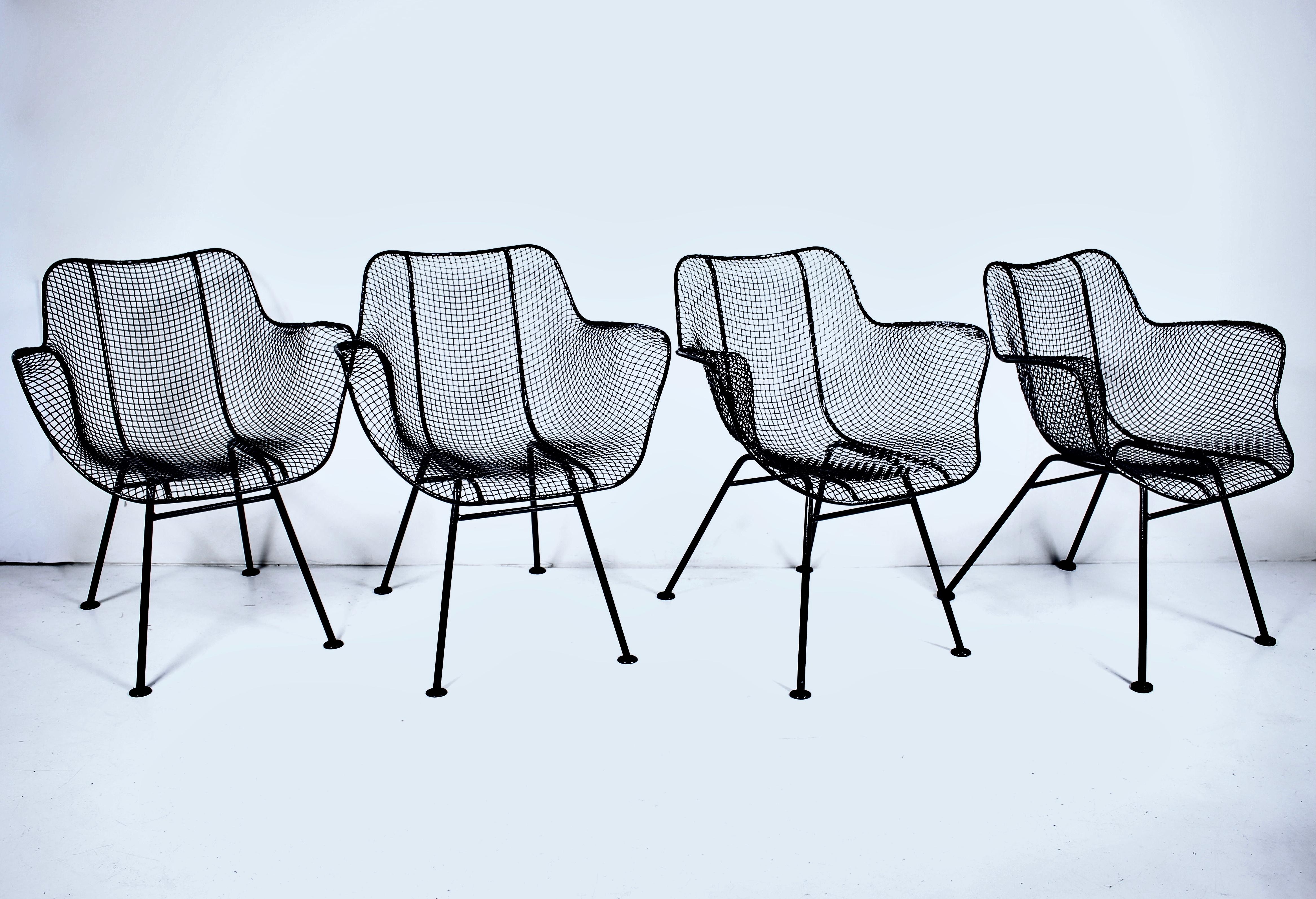 Ensemble original de 4 fauteuils Russell Woodard en fer noir et fil de fer déployé. Structure en fer forgé, assise et dossier ergonomiques en maille métallique noire sculptée, pieds plats. Places assises à l'intérieur et à l'extérieur. Classique.