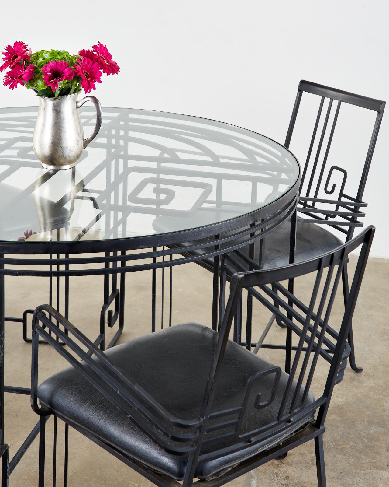 Whimsical set of four wrought iron garden or patio dining chairs. Crafted in the Art Deco taste featuring large neoclassical Greek key motifs on the back splat and feet. Reminiscent of John Salterini's Mid-Century Modern designs of iron furniture