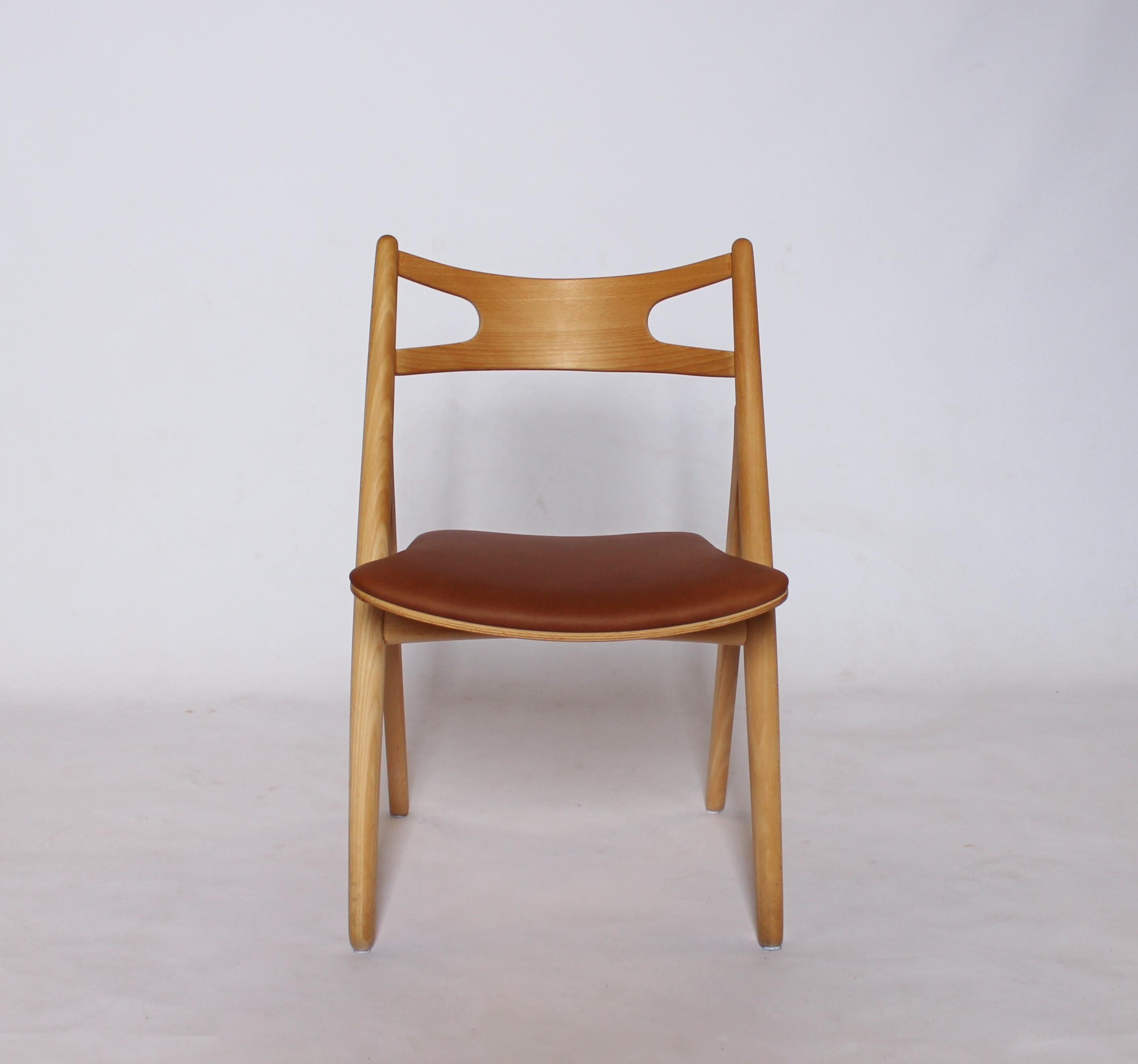 A set of four Sawbuck chairs, model CH24, designed by Hans J. Wegner in 1952 and manufactured by Carl Hansen & Son in the 1970s. The chairs are made of soap treated beech and with seats of cognac elegance leather.