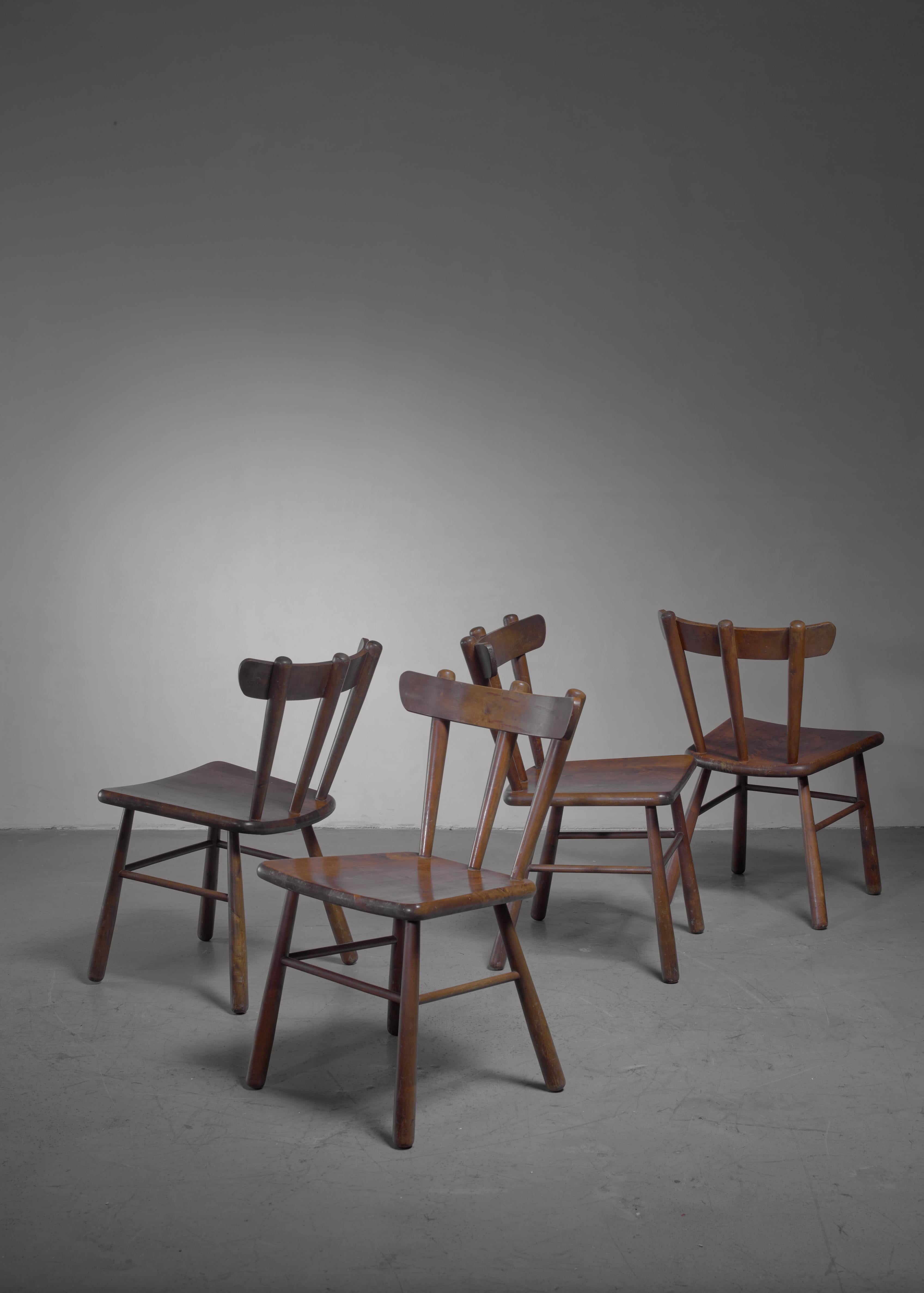 A set of four Scandinavian Modern wooden dining or side chairs with rounded legs and a curved spindle backrest.

   