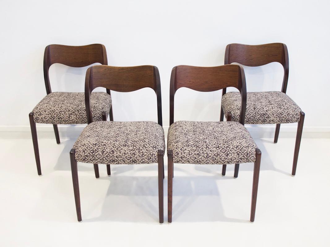Set of four N. O. Møller model 71 dining chairs with solid and veneered hardwood frame. Designed in 1951 and manufactured by J. L. Møllers Møbelfabrik. Seats reupholstered in beige fabric with navy pattern. Feet with white plastic shoes.
