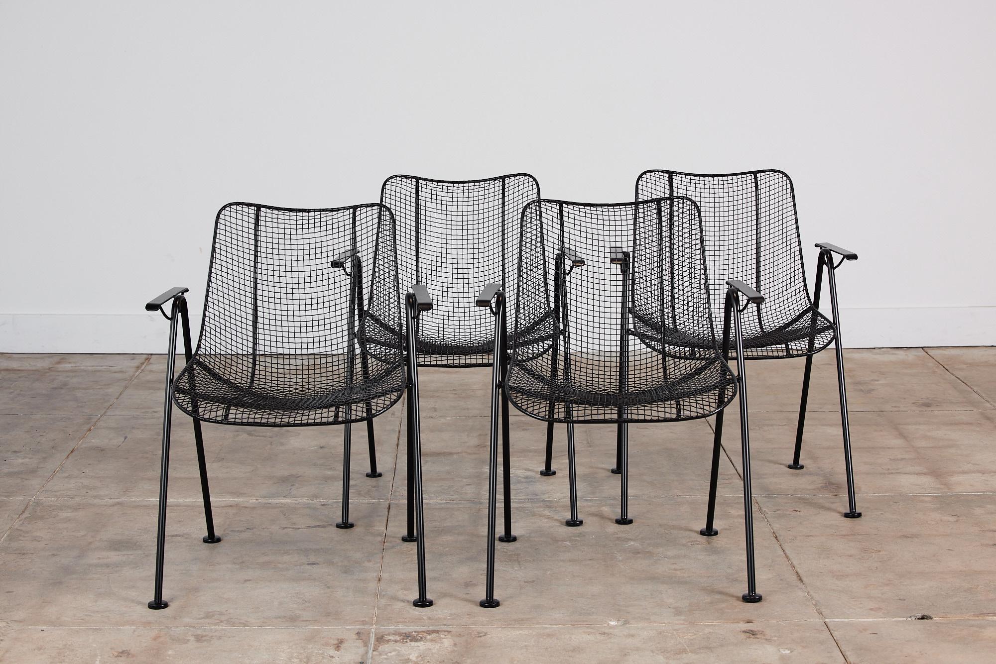 Set of four dining armchairs by Lee Woodard for Woodard Furniture, c.1950s, USA. The armchairs are from Woodard’s “Sculptura” line designed in 1956. Each chair has a molded mesh frame that sits atop four wrought iron legs with disc feet. The chairs