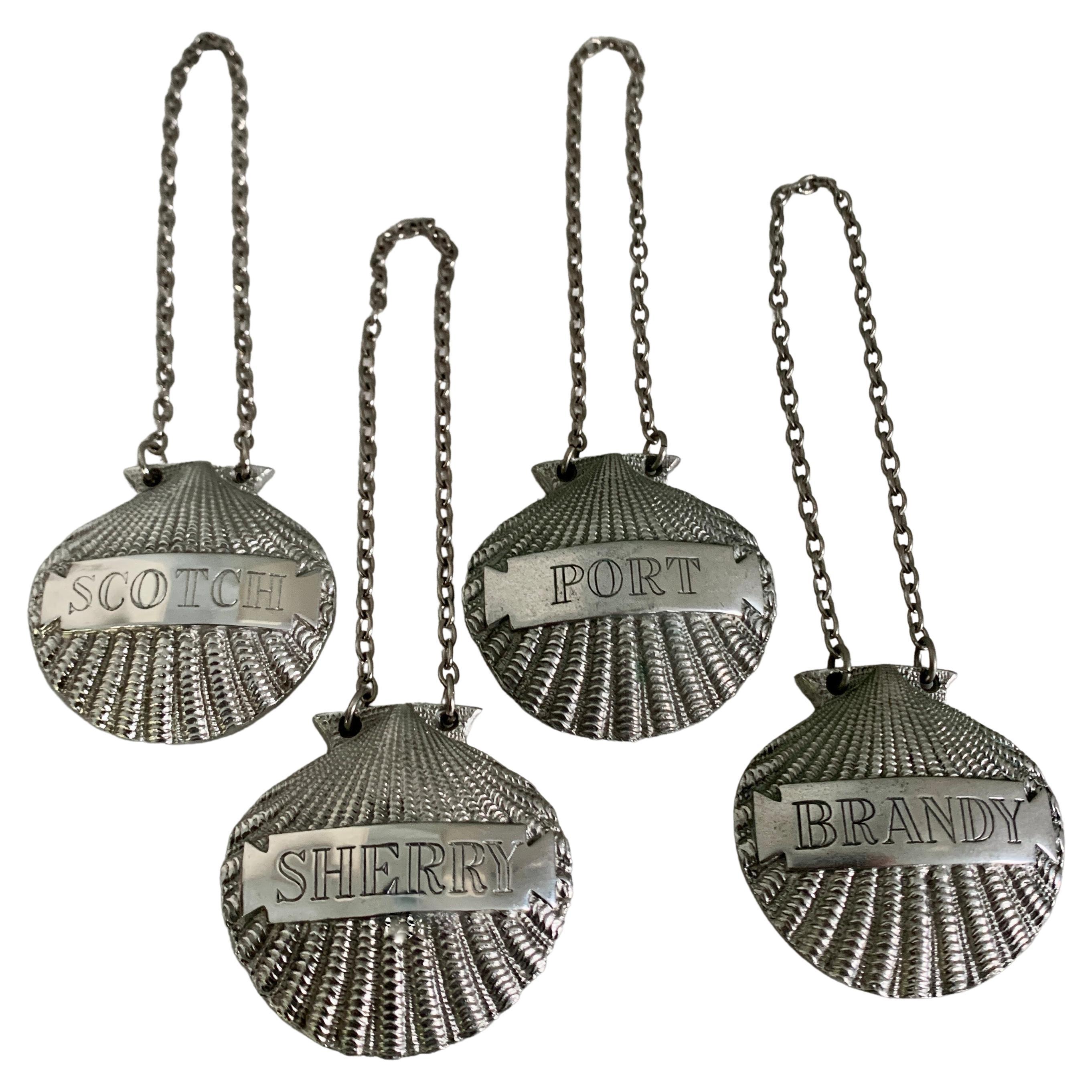 A very sophisticated, made in the U.K., set of 4 Liquor Hanging labels. The shell motif is polished pewter with a silver chain that easily slips over your existing decanters. 

Labels for Port, Sherry, Scotch and Brandy - a compliment to any bar