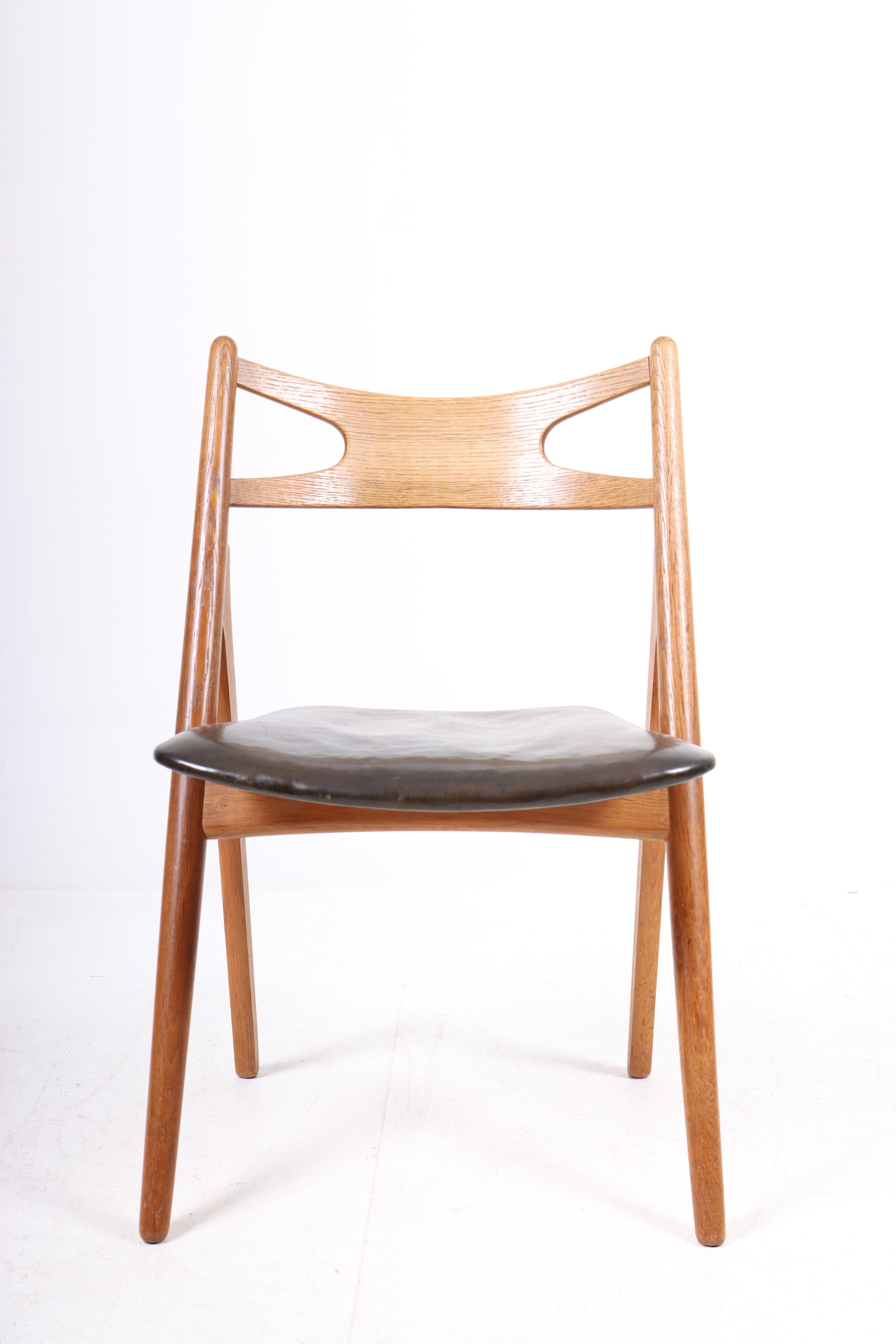 Set of four side chairs is in oiled oak and original patinated leather. Designed by Hans J. Wegner and made by Carl Hansen & Søn in the 1950s. The model name is CH29.