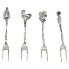 Set of four silver appetizer forks with figures in perfect shape on the handles