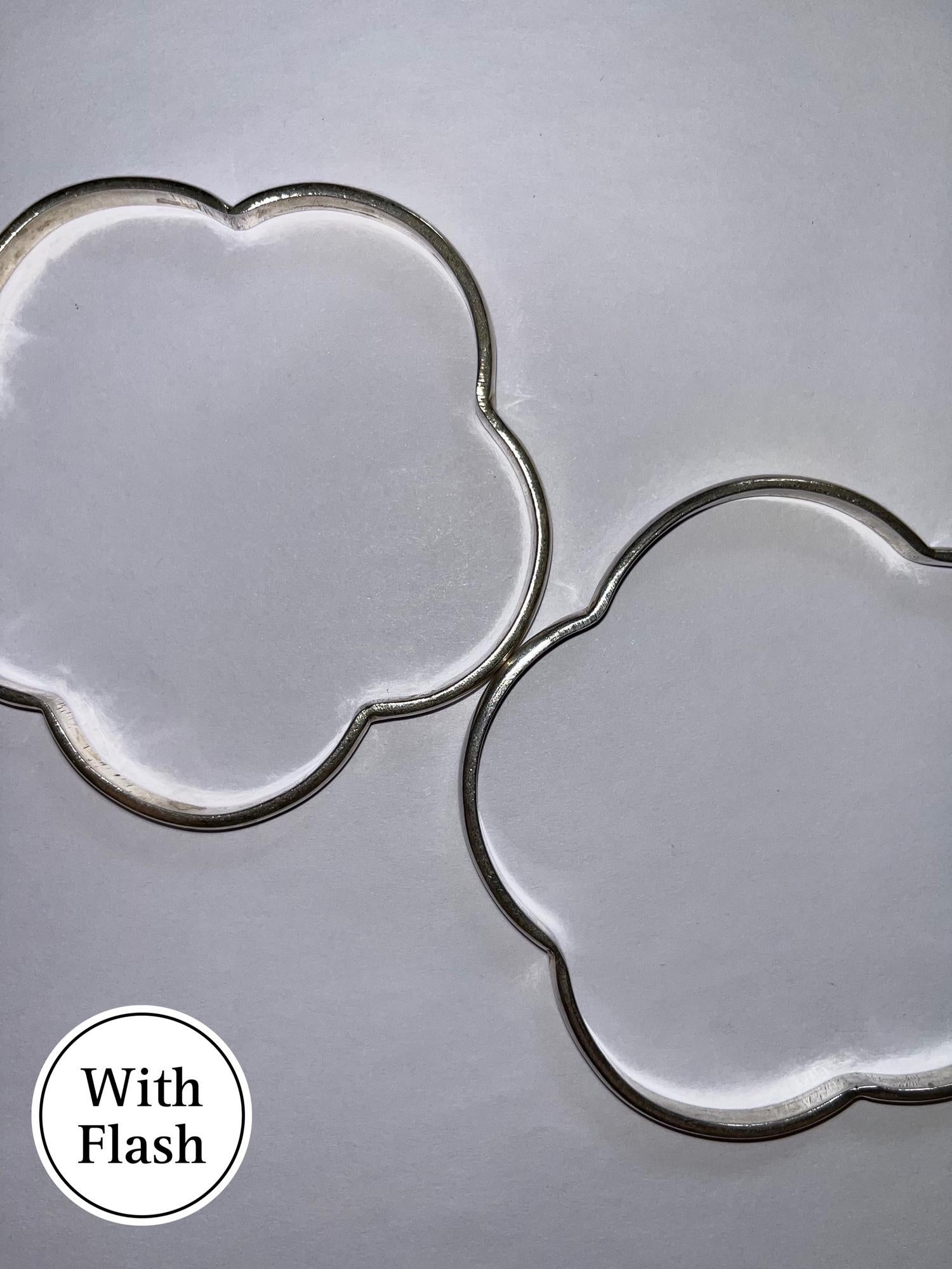 This set is composed of four flower-shaped bangles. The four bangles are silver-toned. The design is delicate with the slimness of the four bracelets. No hallmarks appear on any of the bangles. 

Measurements are rounded off. The weight indicated is