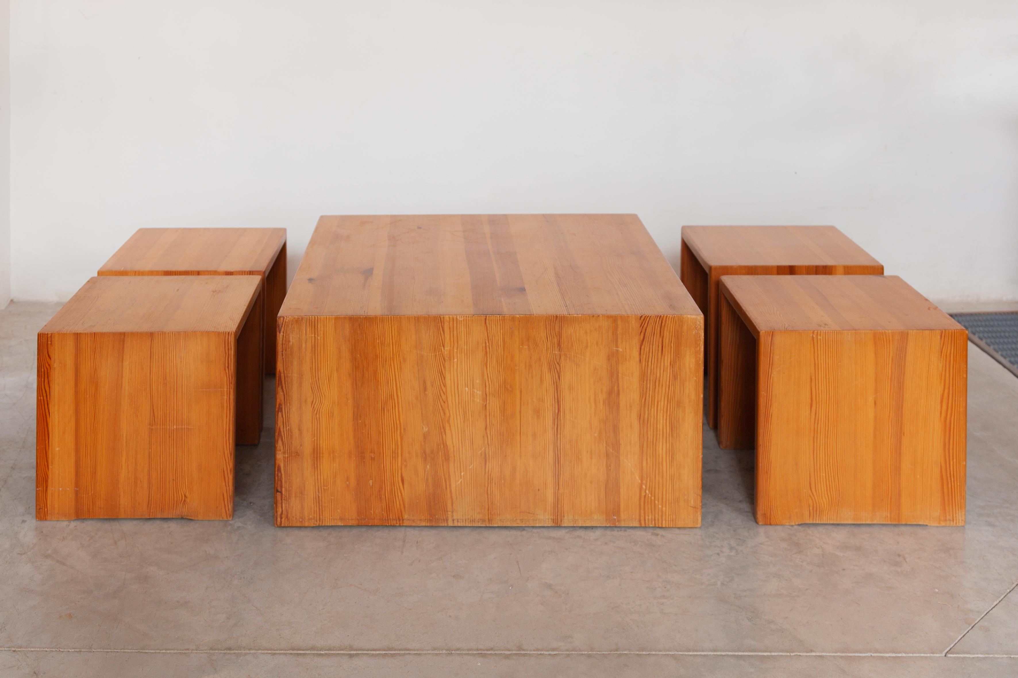 Cet ensemble de quatre tabourets et d'une table a été conçu dans les années 70. Il est composé d'une structure entièrement en pin. La patine visible montre toute l'authenticité de ces pièces qui ont traversé le temps. Avec ses lignes raffinées, cet