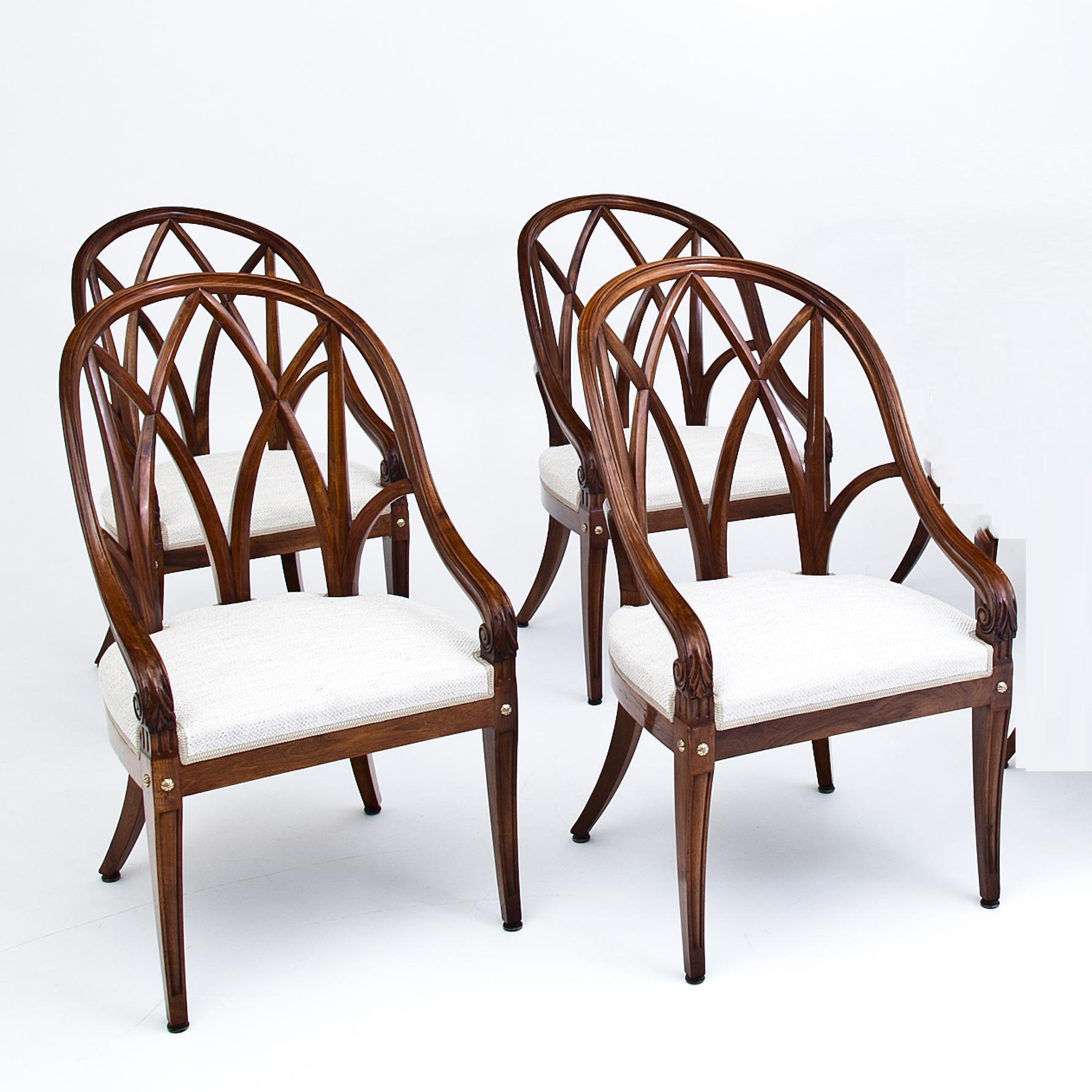 Set of 4 elegant French armchairs with exquiste, curved backrests out of solid walnut. The armrests end in volutes and rest upon the tapered front legs. These are decorated with round brass rivets and are fluted. The backsides show each a small