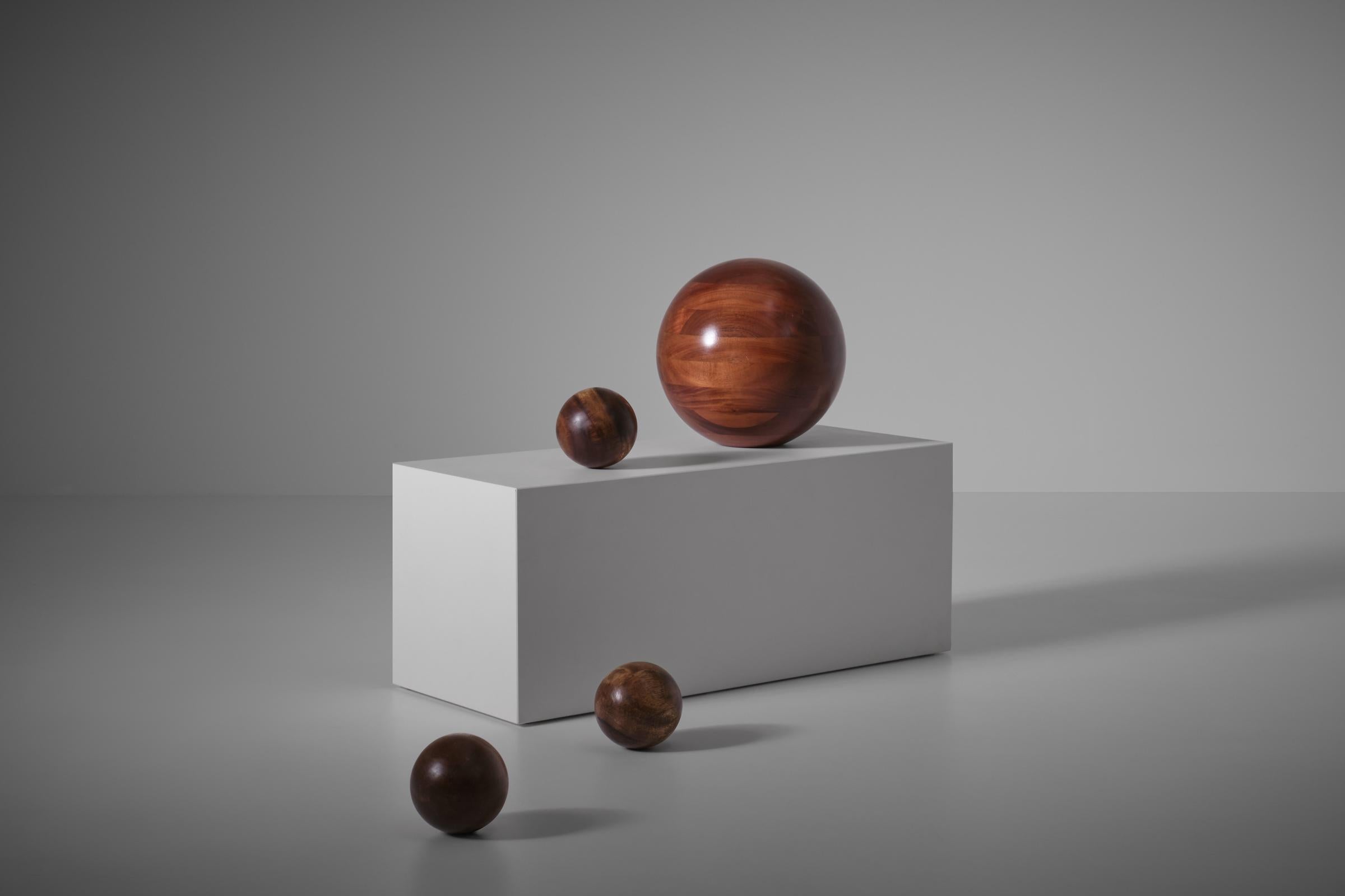 Set of four solid wooden balls, 1970s. Playful and decorative set made from solid Iroko wood crafted by hand in the 1970s by a specialized wood turner. The three smaller balls are ball shaped all around but once found their position the lay stable