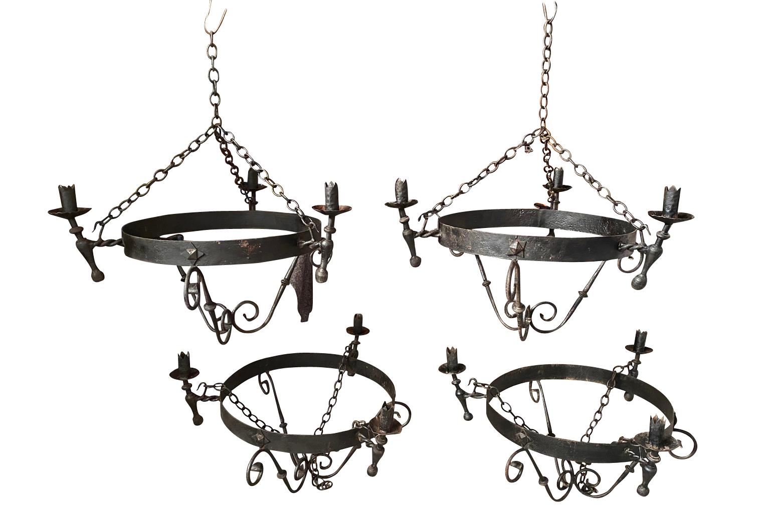 A very handsome set of four chandeliers from Spain. Beautifully constructed from hand forged iron. Stunning statement pieces.