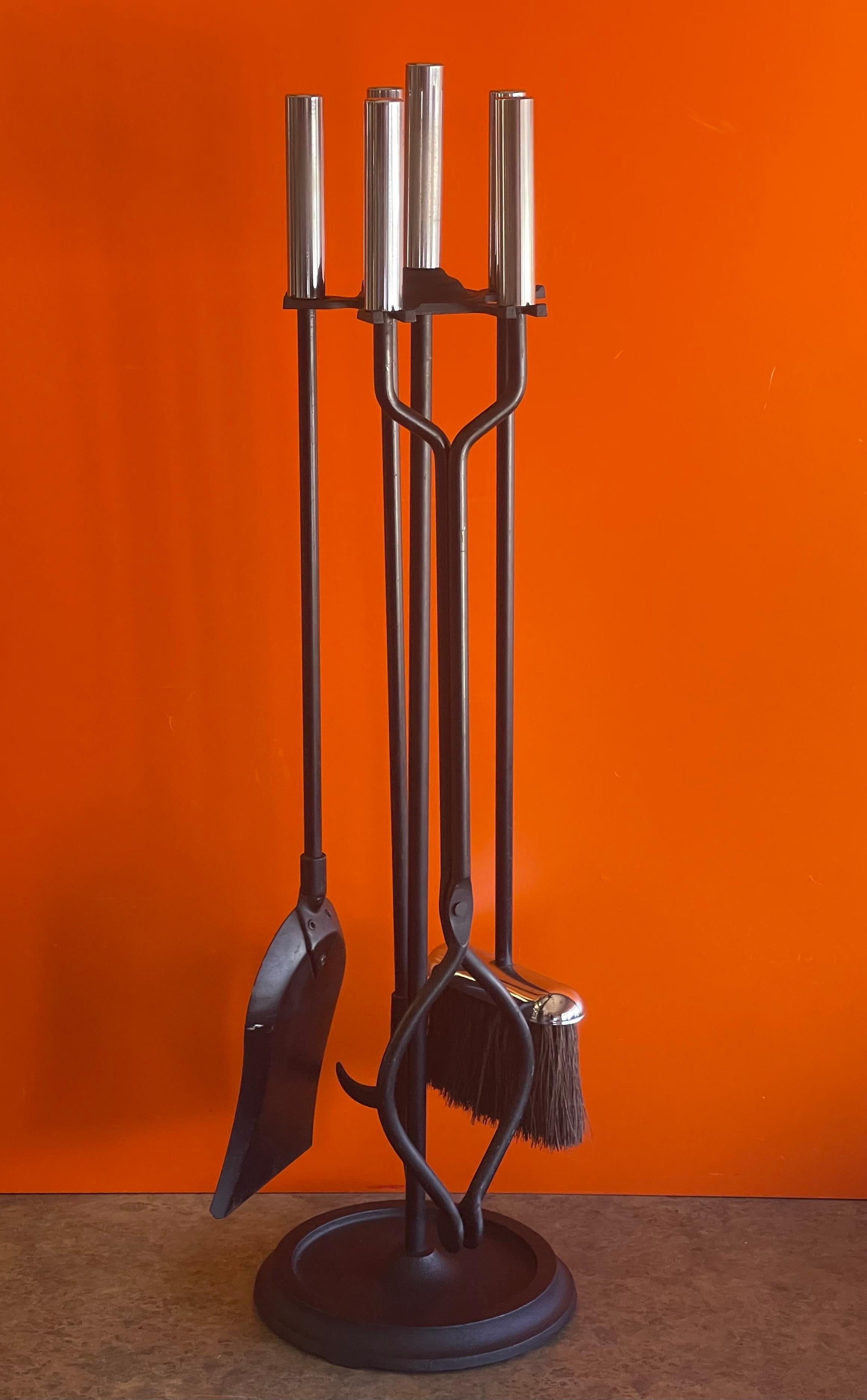 Modernist set of four stainless steel handled fireplace tools and stand, circa 2000s. There are four tools (shovel, brush, log holder and poker) and a single column stand in very good vintage condition. The set is very heavy and well made; it