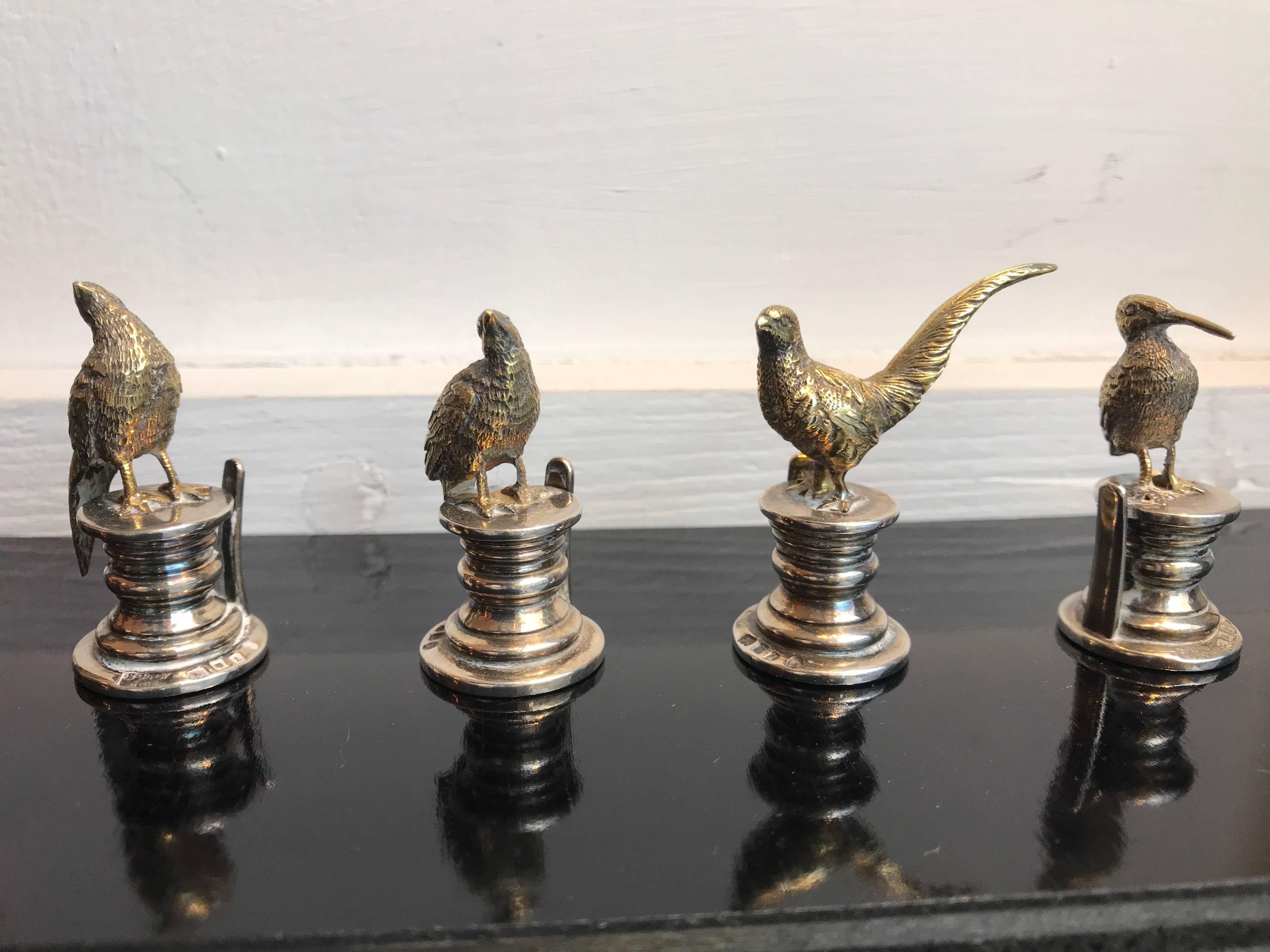 A set of four cast sterling silver place card holders, birds hallmarked at the base by the silversmiths E.H.W. & Co, London, 1914-1915. They are four different species of birds, in different positions. Each bird stands on a circular base, has a very