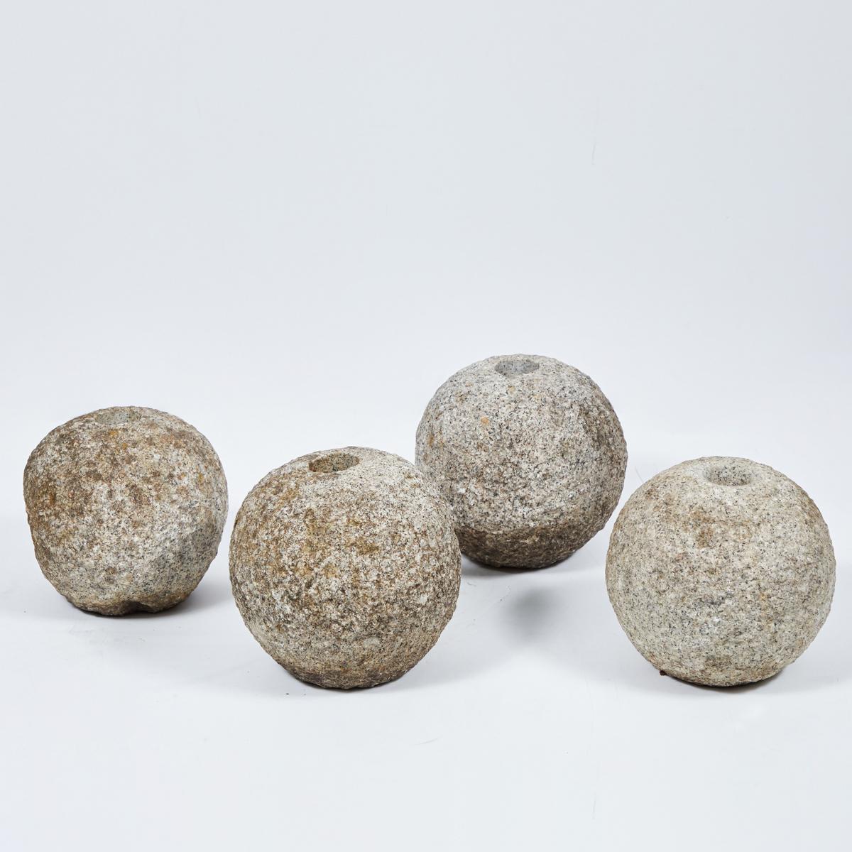 A set of four stone balls, originating in England, circa 1900.