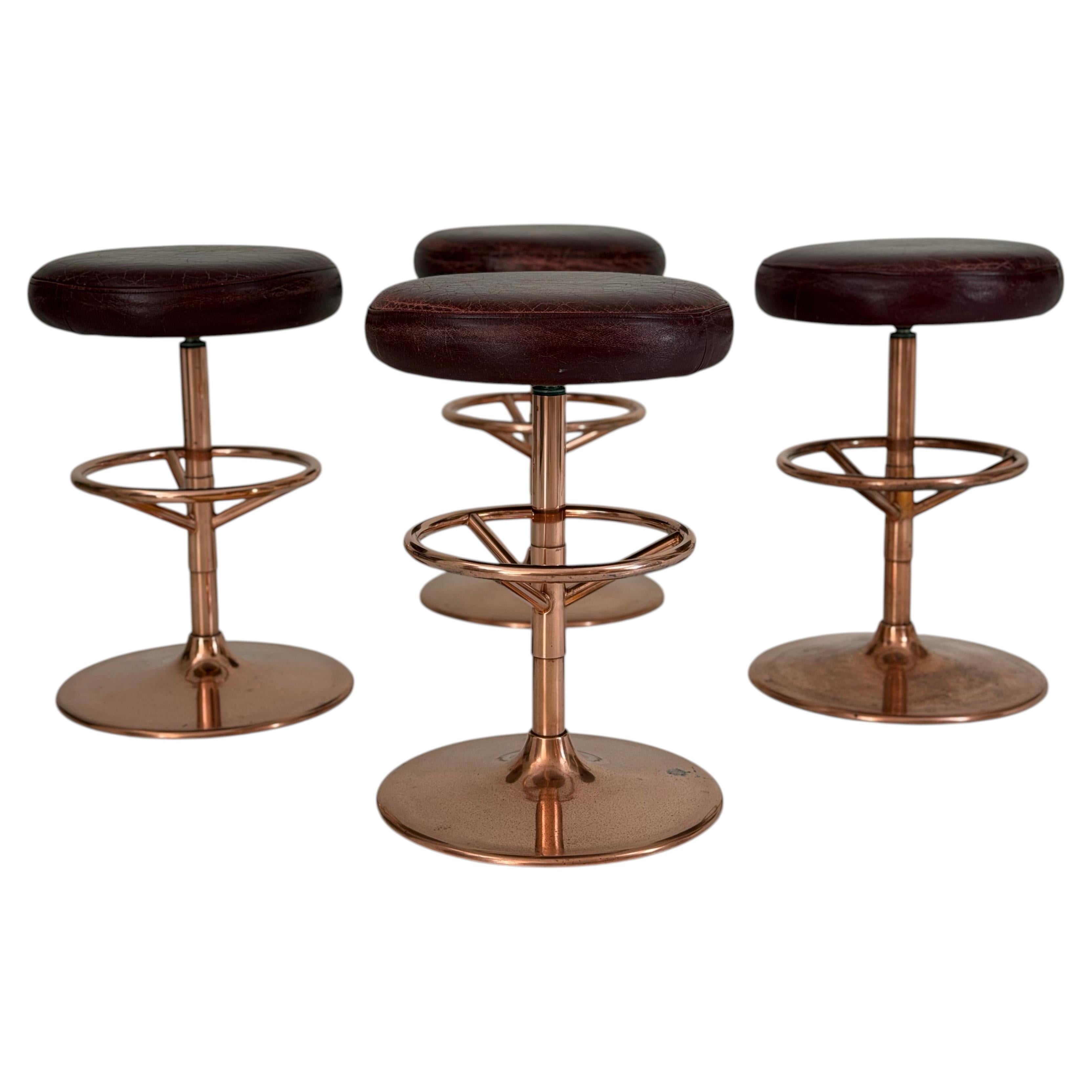 Set di quattro sgabelli girevoli, in metallo placcato rame con rivestimento in pelle color rosso scuro, di produzione americana