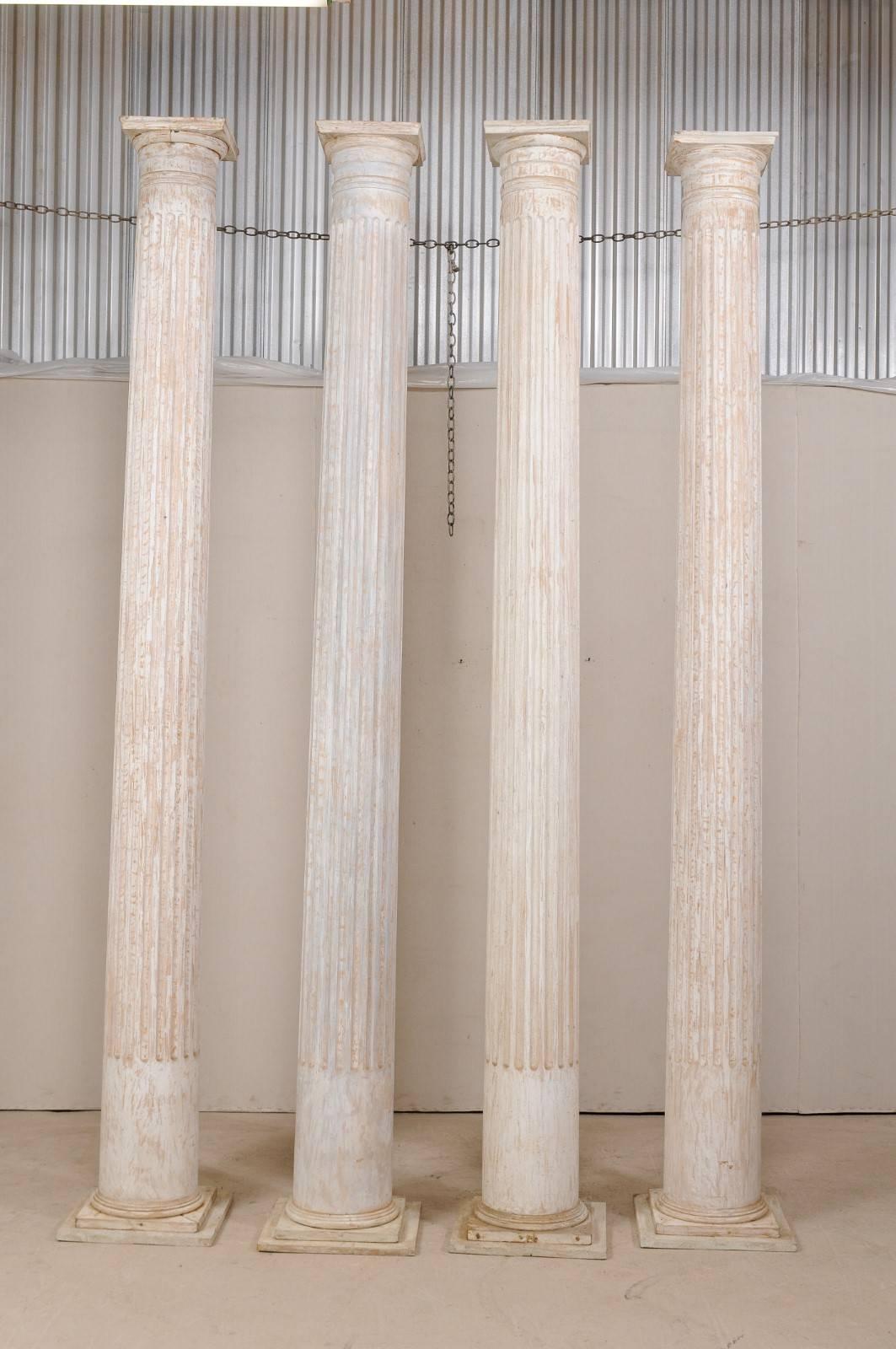 A set of four American mid-20th century Greek Doric style fluted columns. This set of columns, from the early to mid-20th century, stand at an impressive 10.5 feet in height. They are fashioned in the Greek Doric style, rounded columns with carved