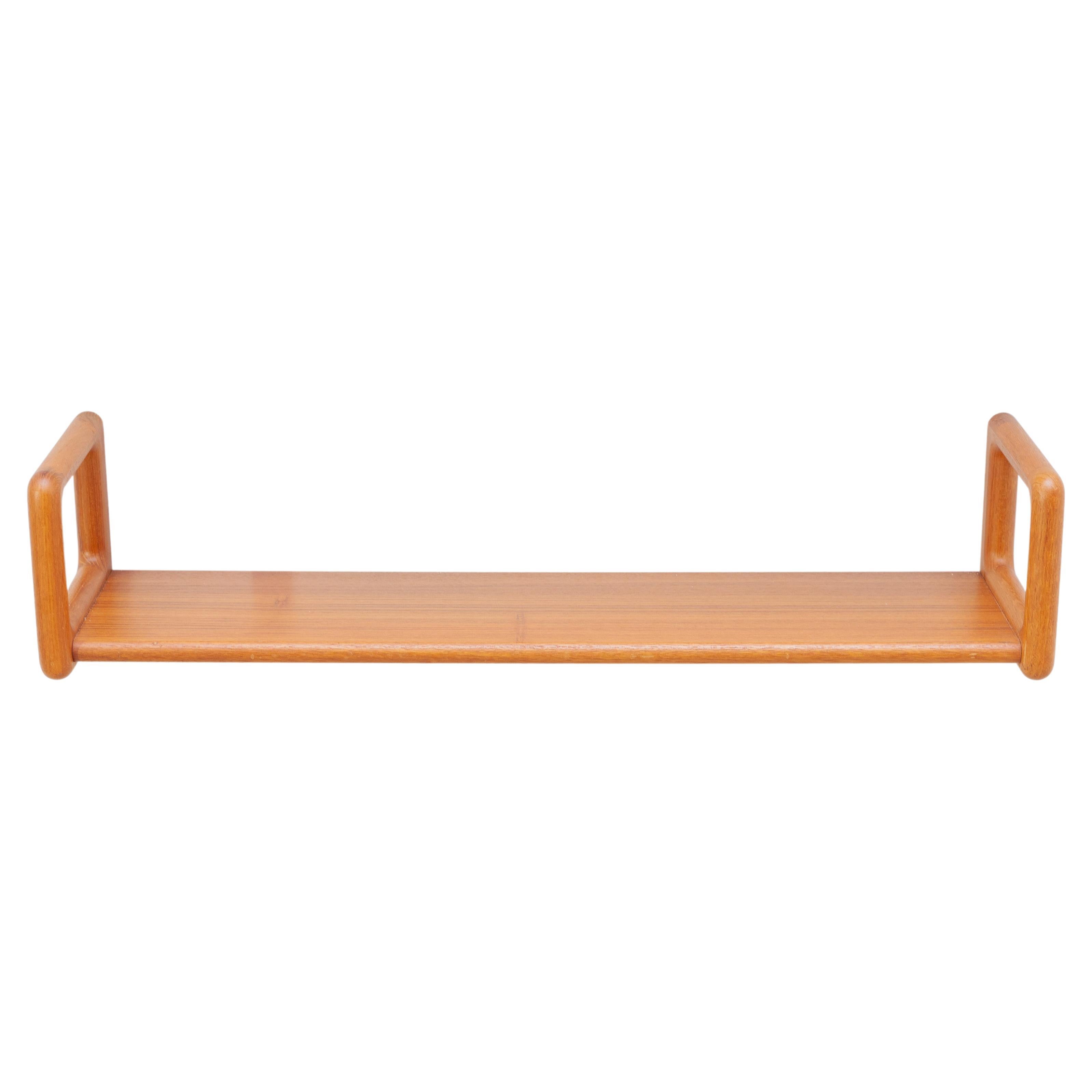 Danish teak wall shelves in classic midcentury design by Kai Kristiansen. Hanging style with soft rounded edges.These teak shelves are a perfect example of a simple Danish design. Invisible hardware on the back creates a floating-on-the-wall