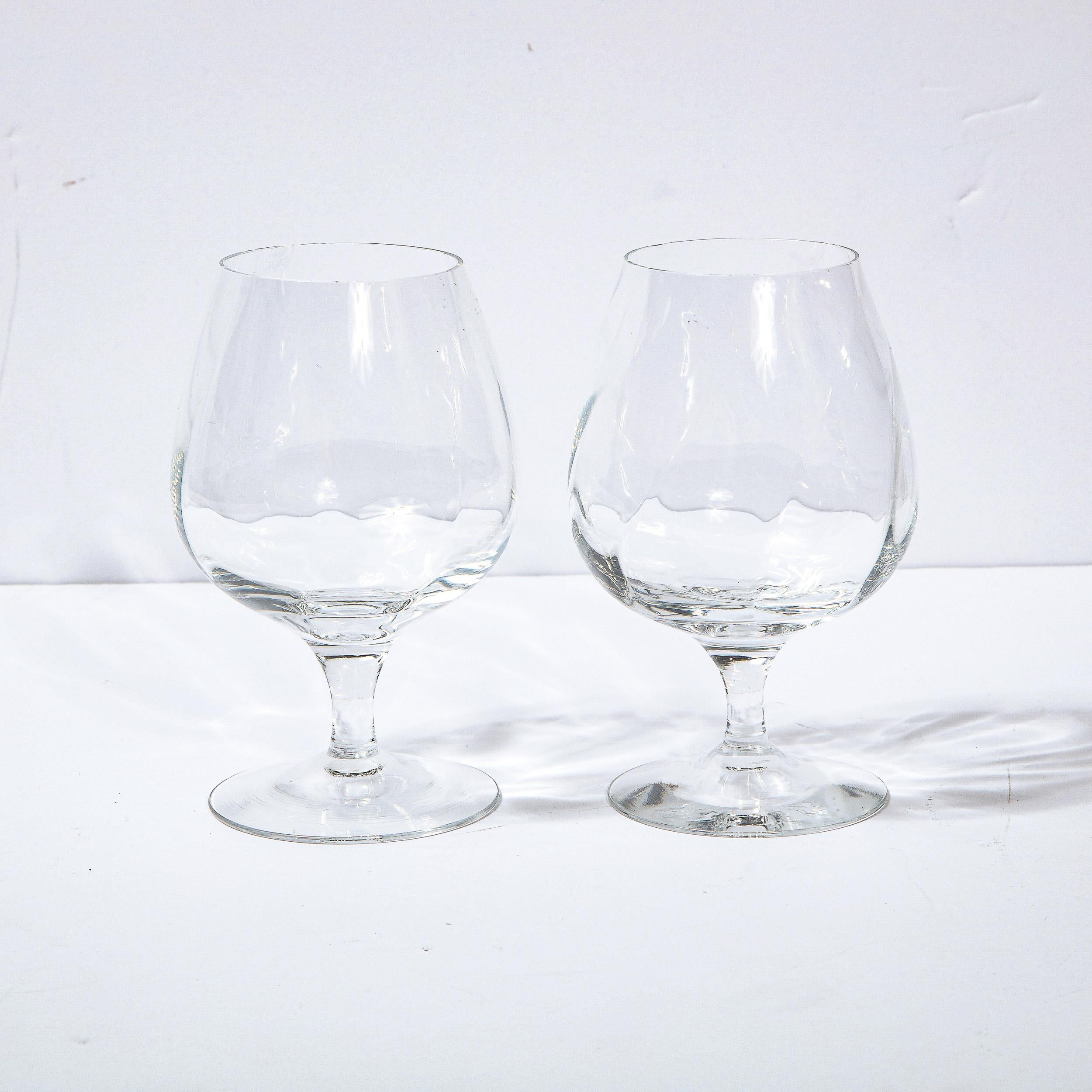 This stunning set of four brandy snifters were realized by the fabled American company Tiffany & Co. They feature circular bases; cylindrical stems (that flare slightly at their apex); and rounded bodies with subtle channeling detailing at a slight