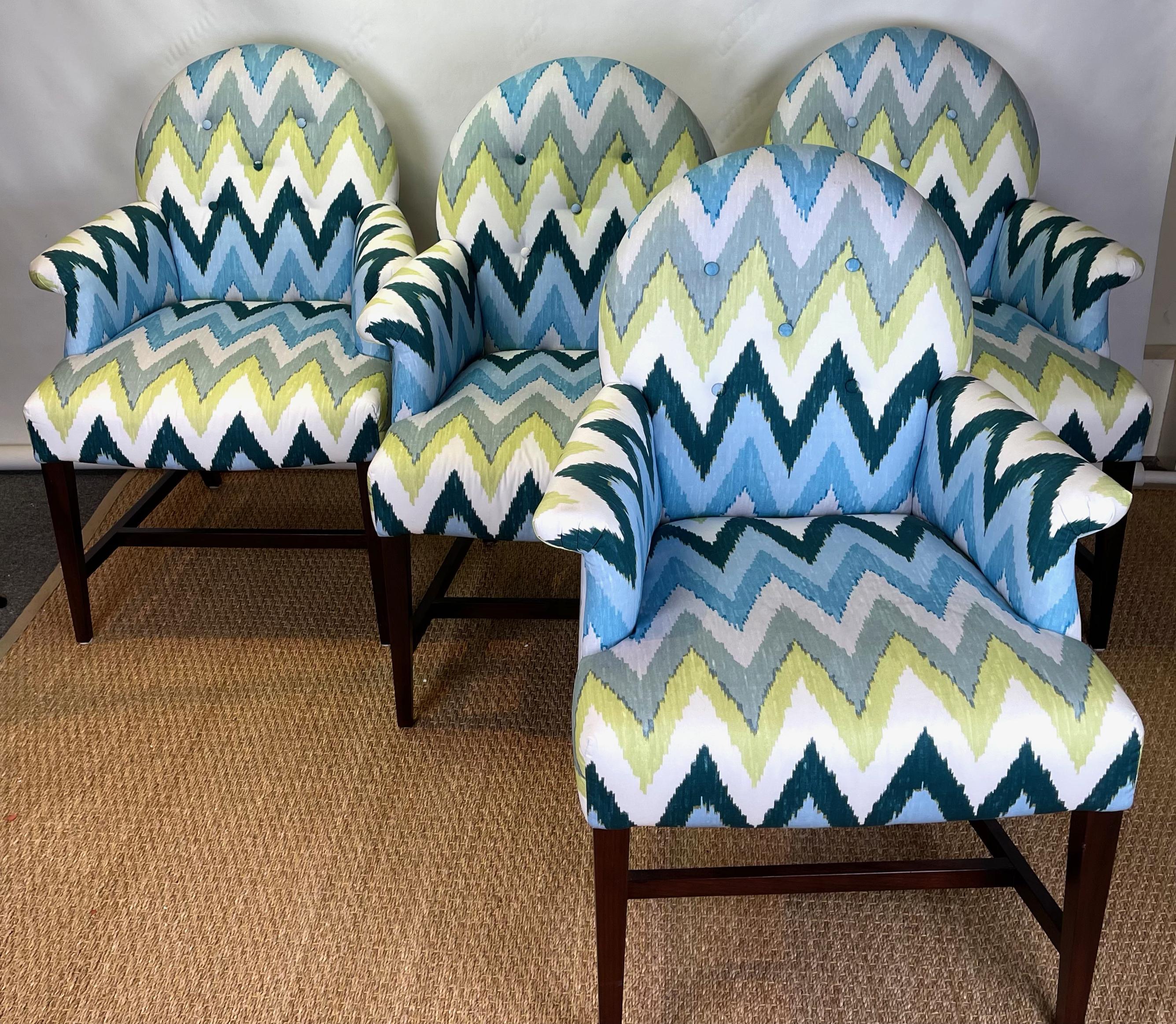 A set of four vintage upholstered arm chairs recently upholstered in a cotton ikat print fabric in blues, gray, white and green, resting on dark mahogany colored square tapering legs. Would make comfortable dining or games table chairs.