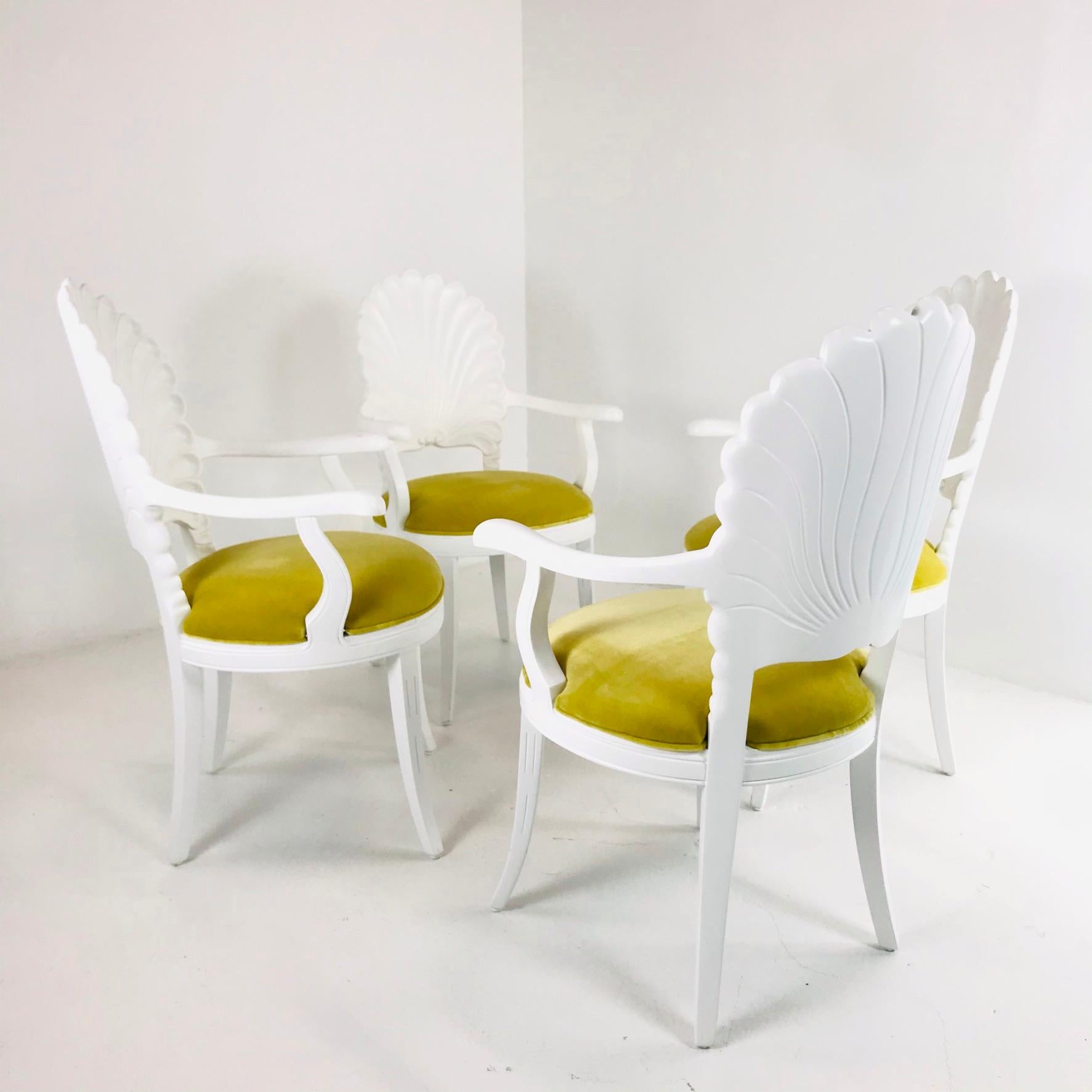 Elegant set of four Venetian Grotto style shell back dining chairs produced in Italy in the Hollywood Regency taste. Features a hand carved frame with a scalloped shell motif back. New white lacquer finish and new luxury yellow velvet upholstery