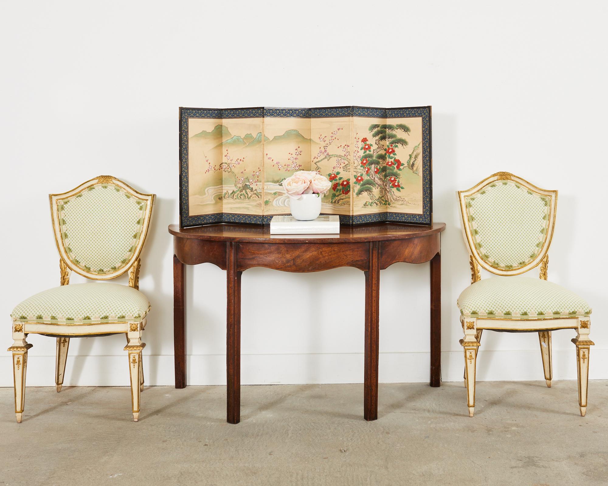 Außergewöhnlicher Satz von vier handwerklich bemalten italienischen Esszimmerstühlen im venezianischen Stil. Die Stühle haben eine schildförmige oder kartuschenförmige Rückenlehne. Die bemalten Rahmen sind mit paketvergoldeten Akzenten und