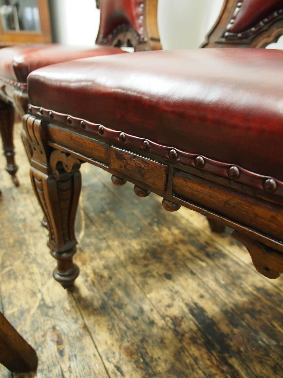 Set of four Victorian carved oak chairs, circa 1860. With shaped top, padded back with deep leather buttons an oval cartouche to the centre, and foliate carving which continues down the sides. They have concave shaped front rails, square, outswept