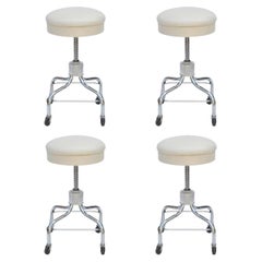 Juego de cuatro taburetes rodantes vintage cromados y de cuero blanco ajustables