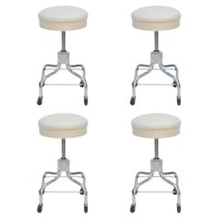 Ensemble de quatre tabourets à roulettes réglables vintage en chrome et cuir blanc